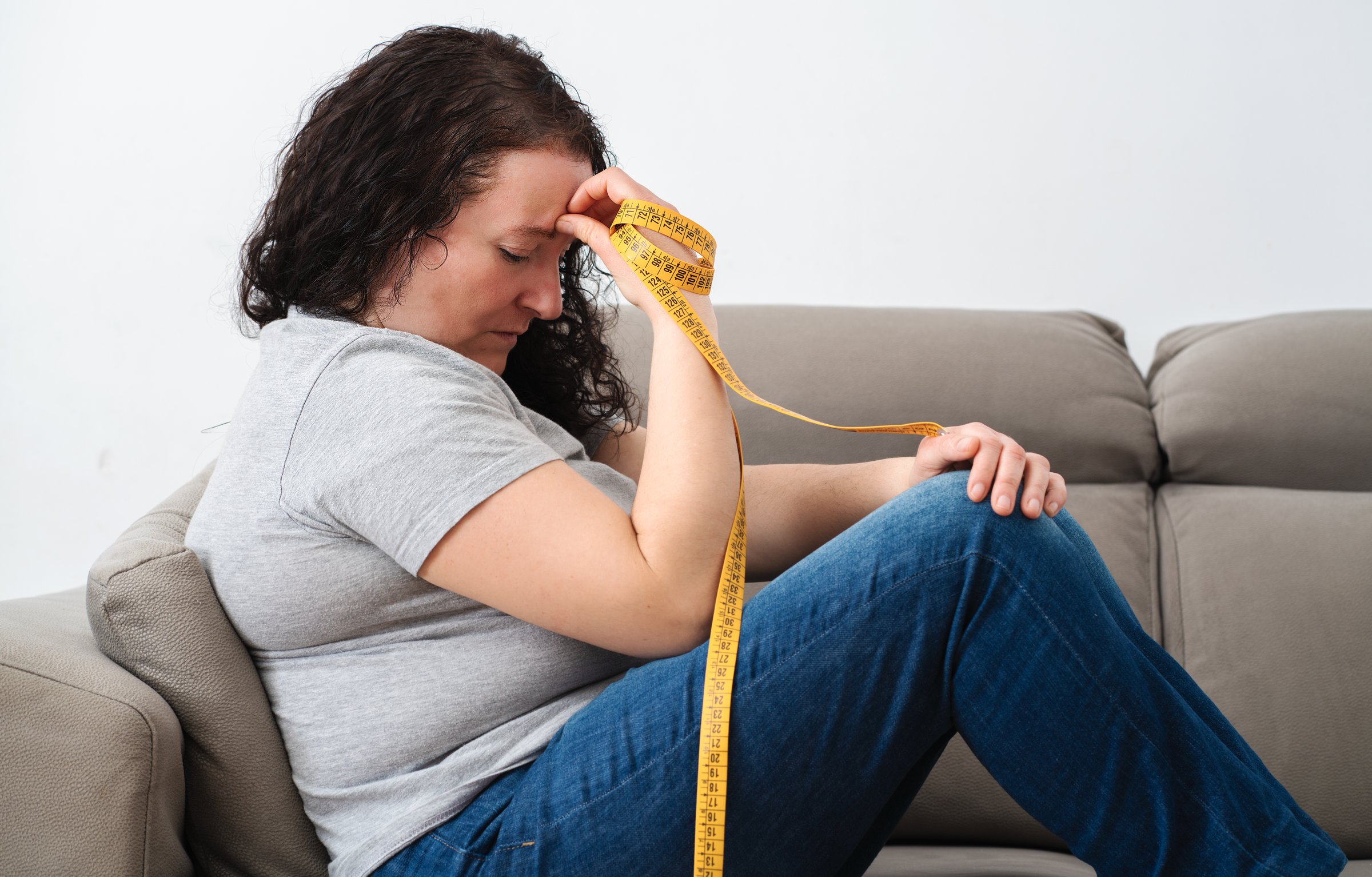 Sad woman obsessed with diet complaining sitting in couch at home