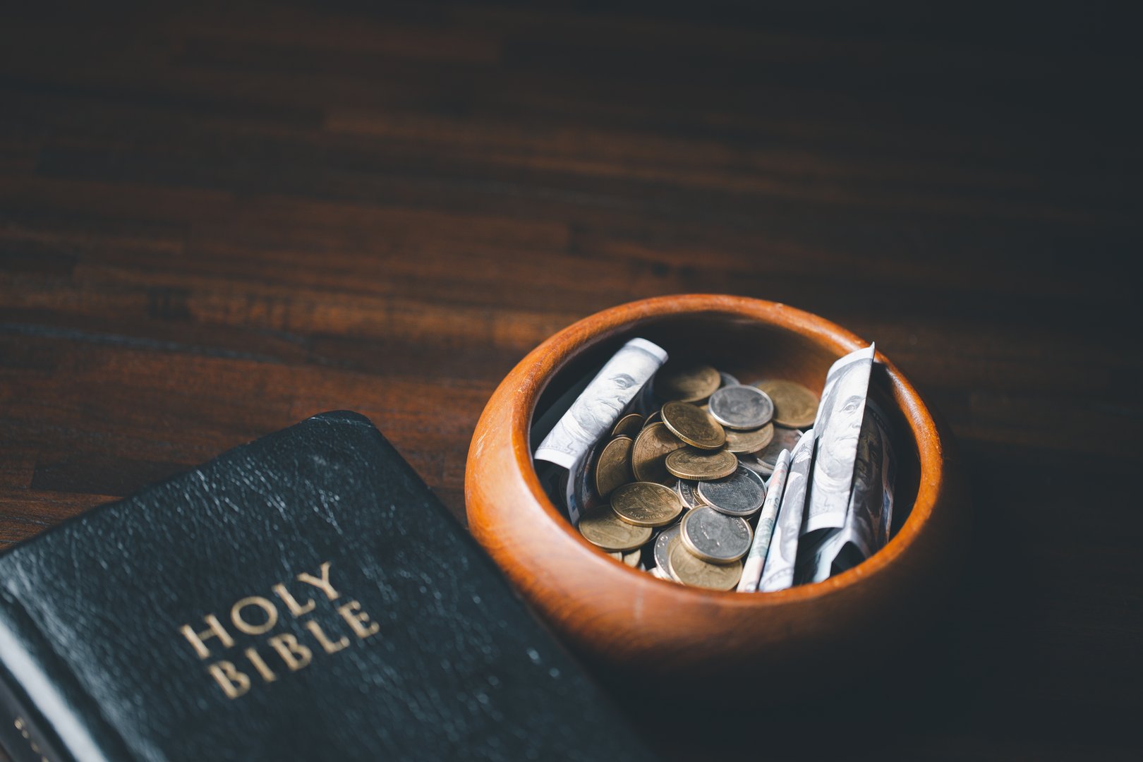 One tenth or tithe is basis on which Bible teaches us to give one tenth of first fruit to God. coins with Holy Bible. Biblical concept of Christian offering, generosity, and giving tithes in church.