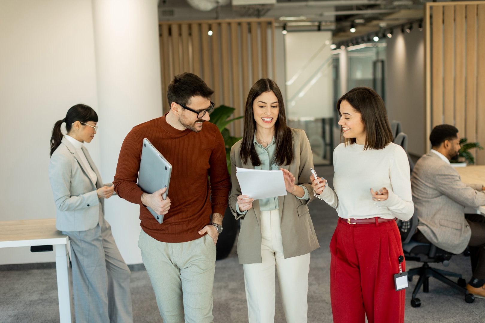 A group of professionals engages in lively discussions while reviewing documents, embodying teamwork and creativity in a bright, contemporary workspace filled with greenery.