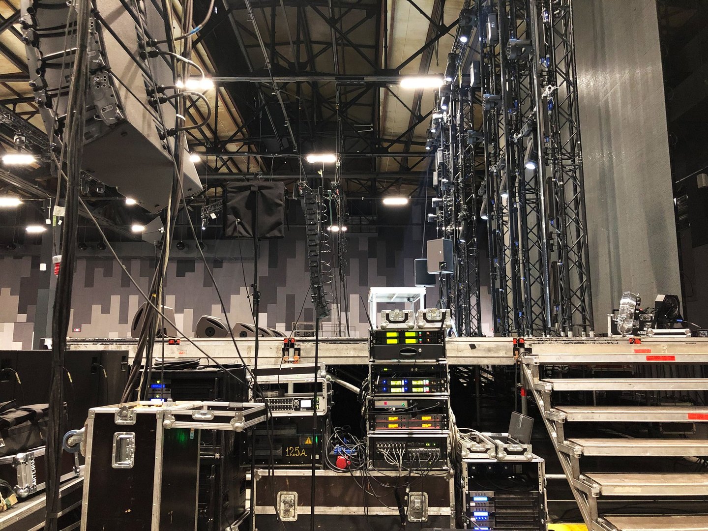 Installation of professional sound, light, video and stage equipment for a concert. Backstage area and tech zone with amplifiers, flight cases and radio microphones.