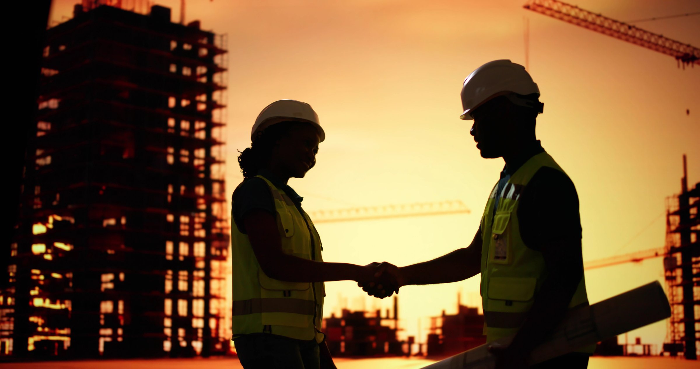 Silhouette Of Two Architects At Construction Site Shaking Hands