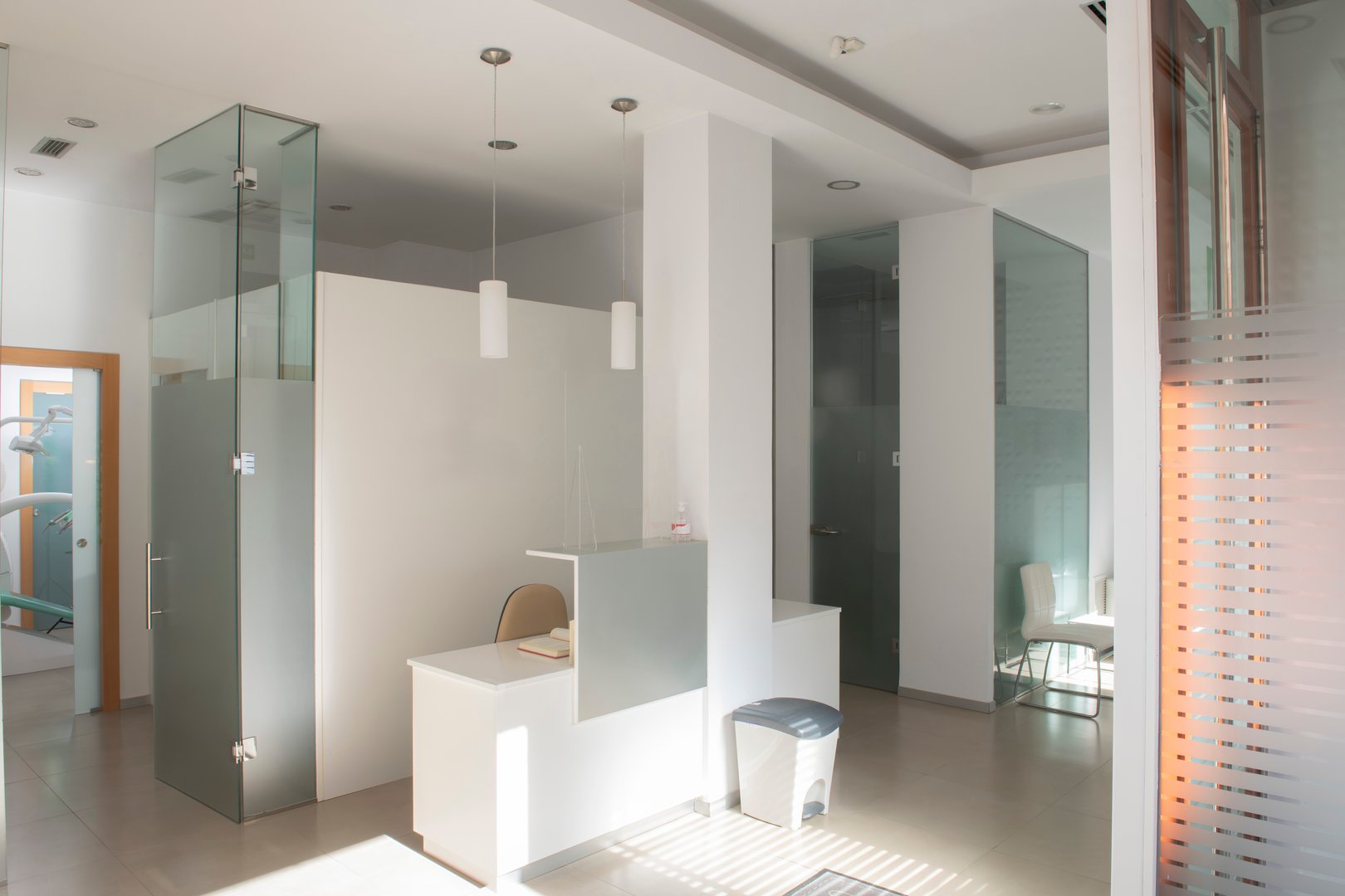 Sunlight illuminating the modern and clean reception area of a dental clinic, featuring glass partitions and a minimalist design