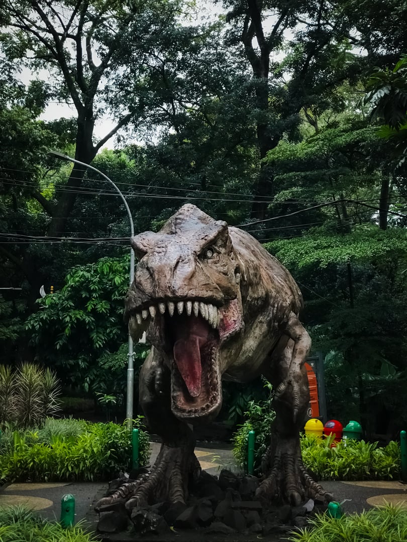 a trex statue in a public park