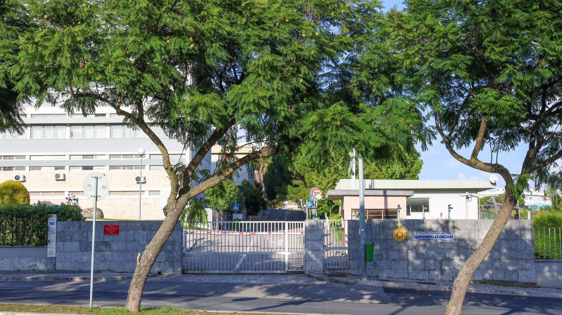 Metal gate of the army geospatial information center - cigeoe - in lisbon, portugal, surrounded by lush trees and vegetation