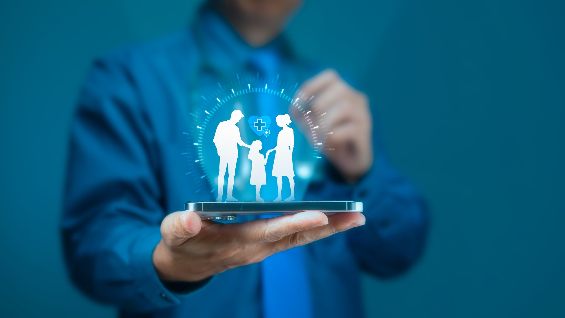 Doctor holds out a smartphone displaying a glowing digital family with a medical cross icon, symbolizing family health protection, medical insurance, and digital healthcare