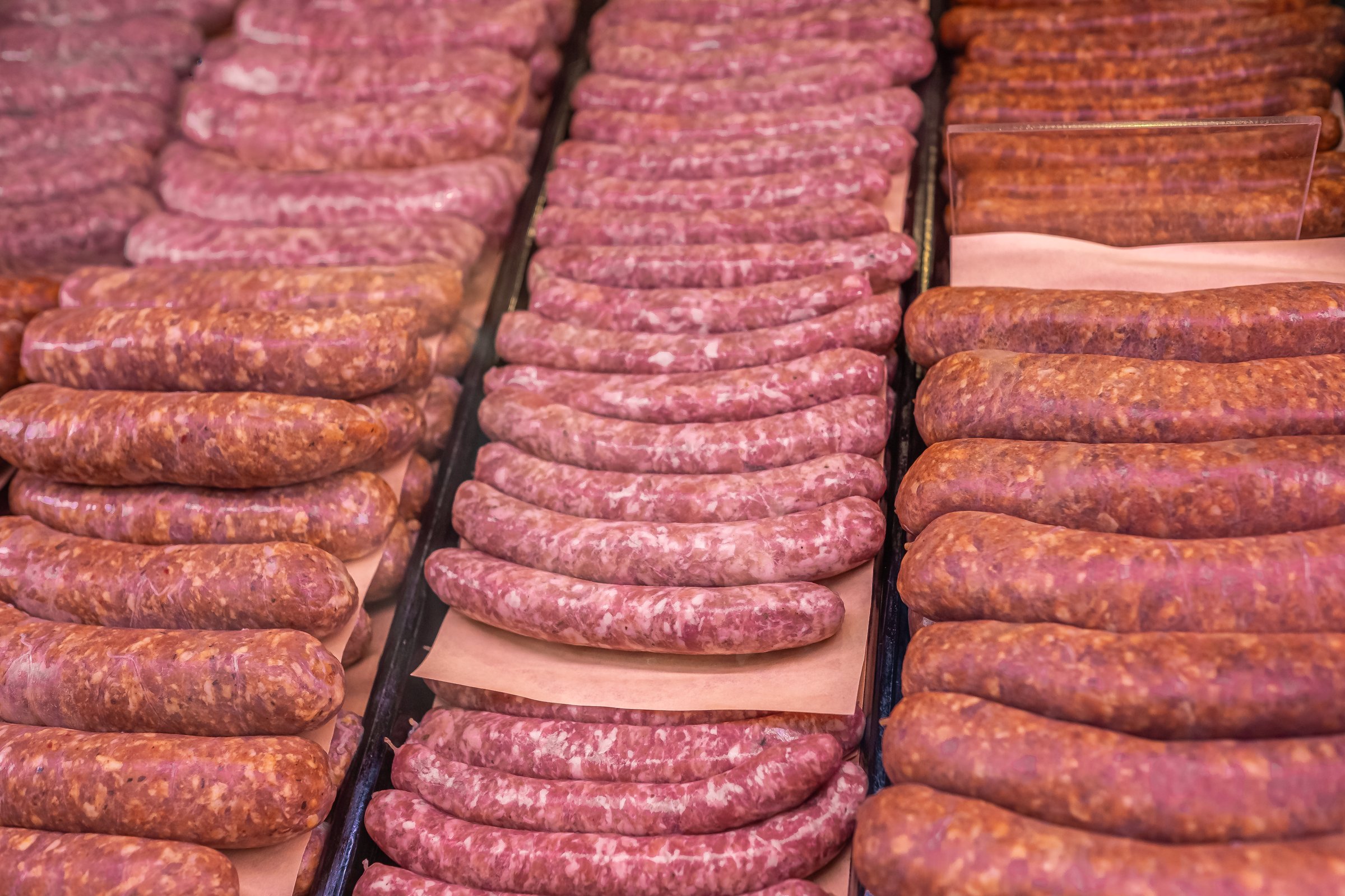 Assortment of meat products layout. Raw fresh sausages for sale in butcher shop display. Food industry concept. Nobody, selective focus
