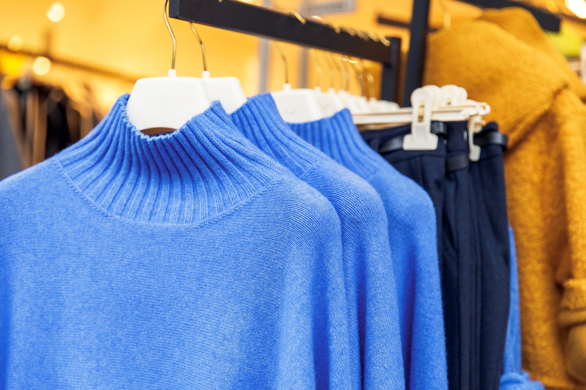 Blue knit sweaters on hangers in a fashion retail store display