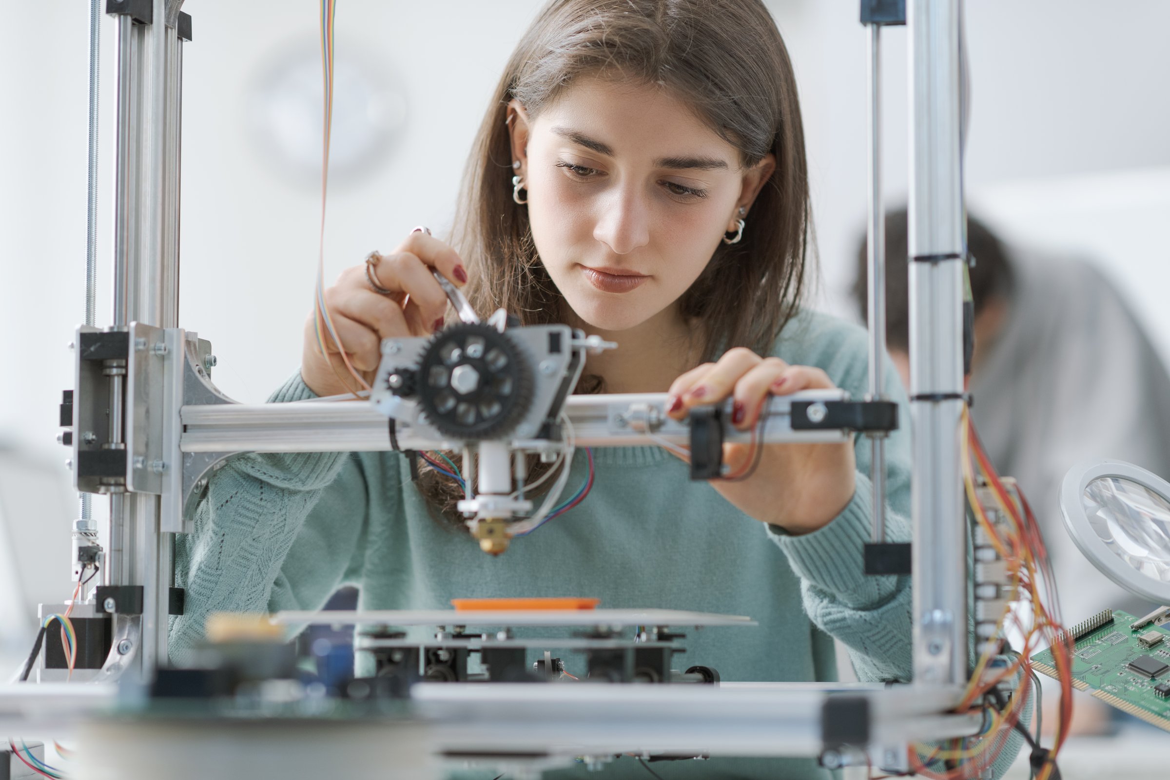 Smart young female student working with a 3D printer in the lab: education and science concept