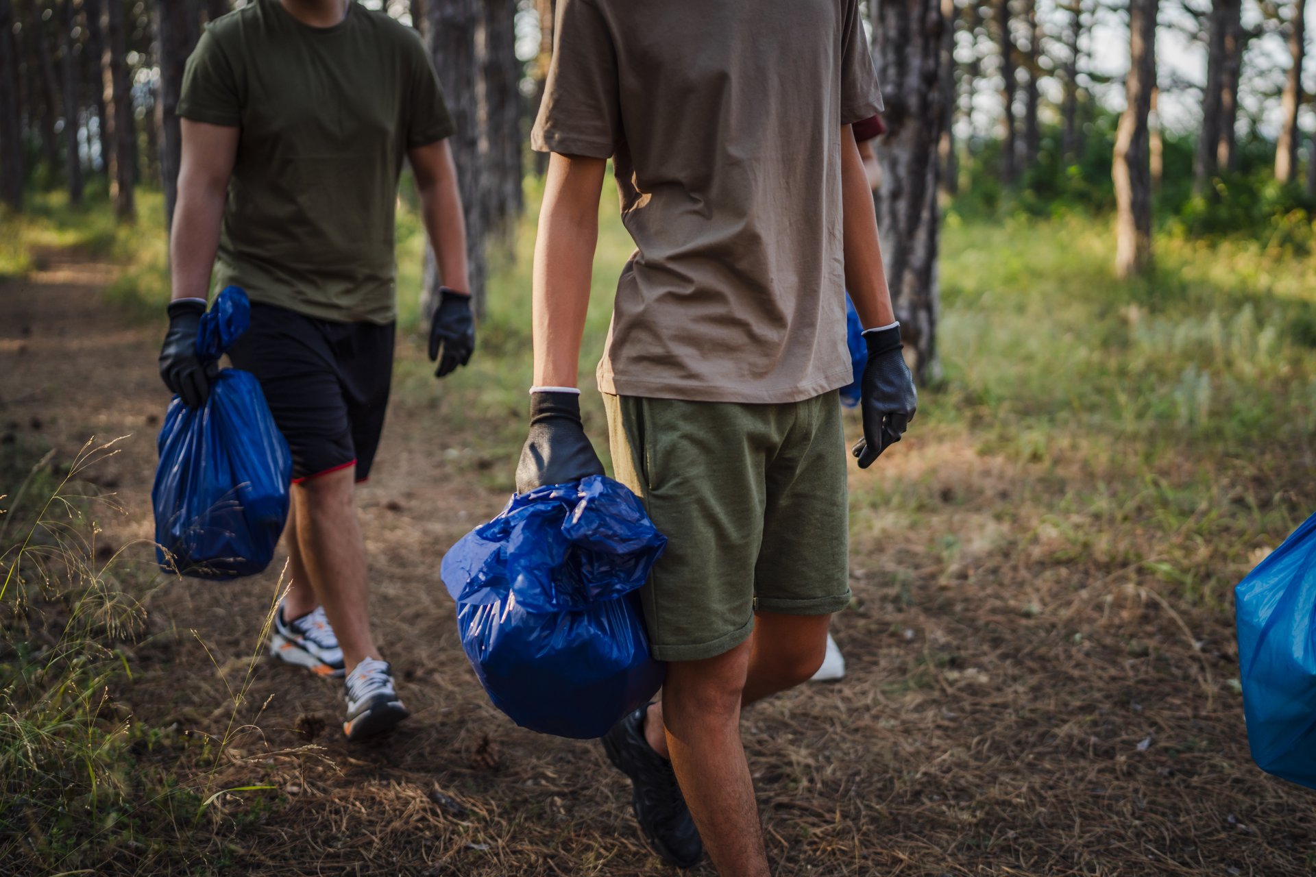 unknown volunteers pick up waste garbage and walk through from forest