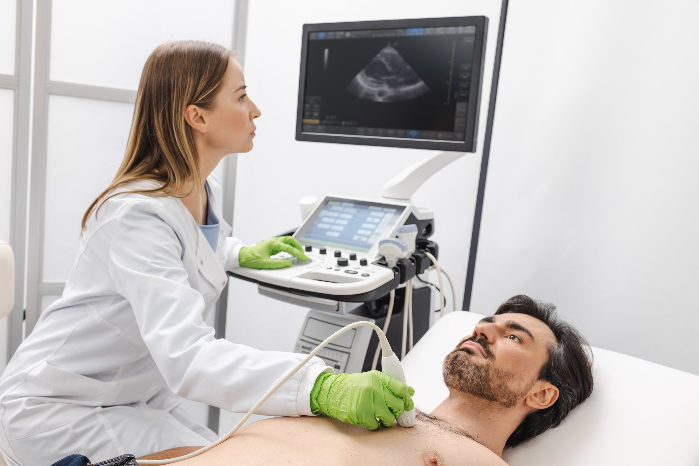 Heart ultrasound exam for male patient with ultrasound specialist while medical exam. Heart health exam with ultrasound scan machine
