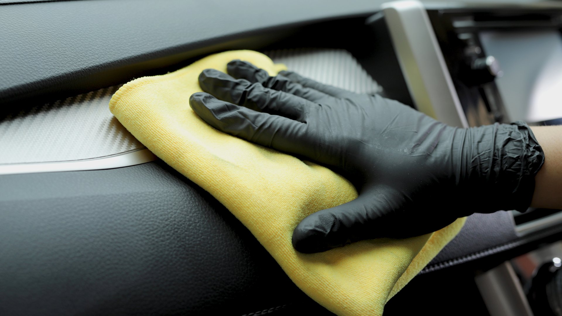 Staff use microfiber cloth to clean cars at car care shop.