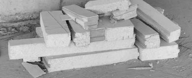 Pile of stacked polystyrene foam boards on a concrete floor, used for insulation or construction purposes.