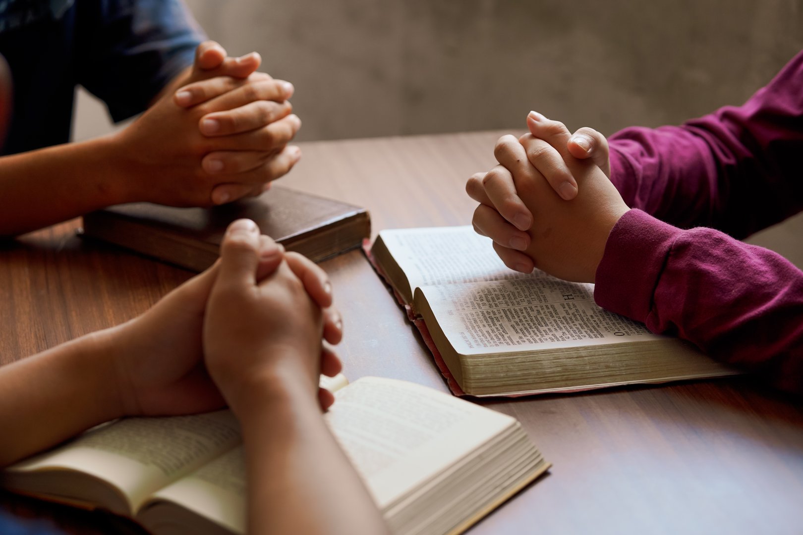 Group Bible study with hands in prayer, reflecting spiritual connection, community, and meditation.