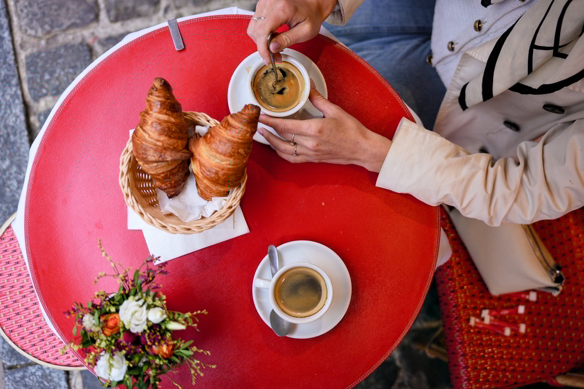 Breakfast scene with coffee and croissants on red cafe table viewed from above