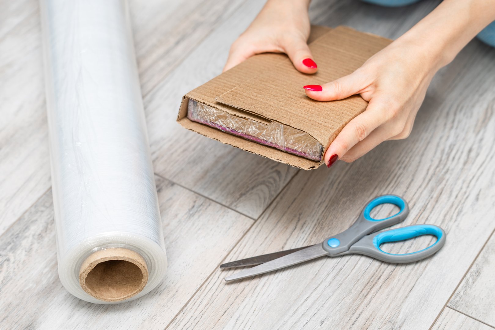 woman packing a book for mailing, close-up. a man is packing a parcel. man packing an online order.