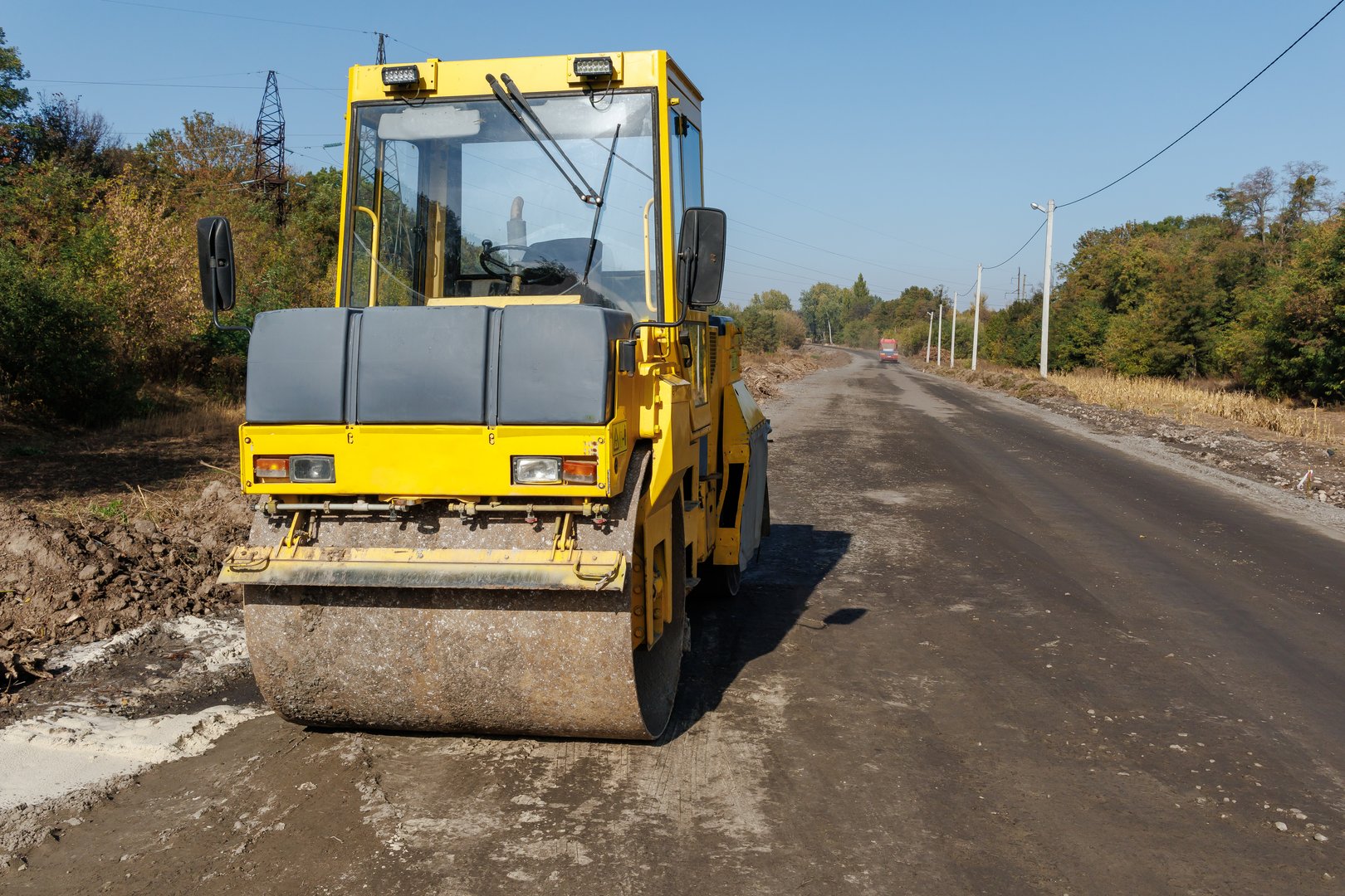 A yellow asphalt rink is parked on the road. A rink used for paving and compacting soil, for laying asphalt or sand during road repair or construction. Road repair works on an asphalt rink.