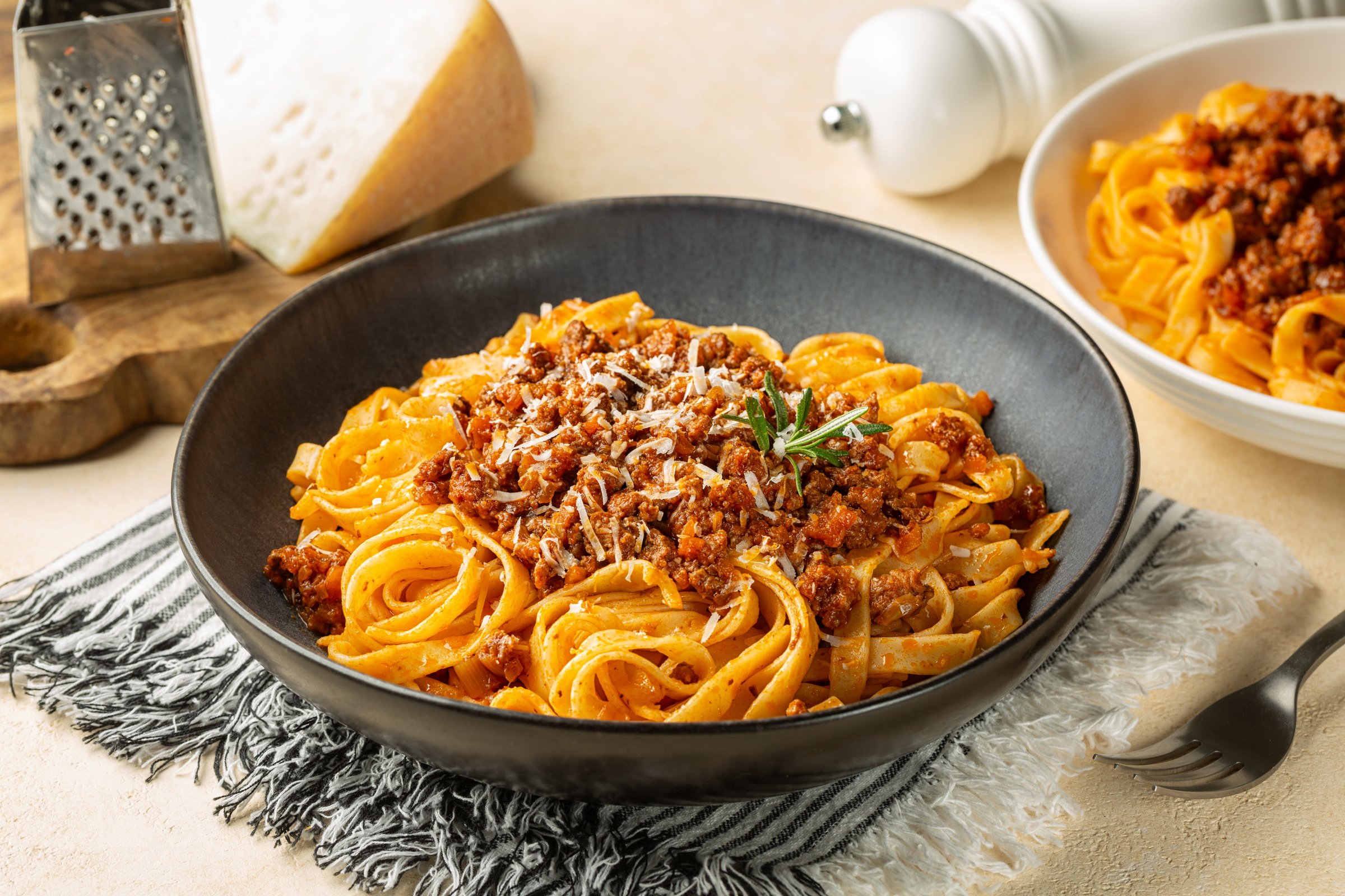 Top view of plate with Tagliatelle al ragu  - long, flat egg pasta with a meat sauce or Bolognese sauce and parmesan cheese, served with rosemary.