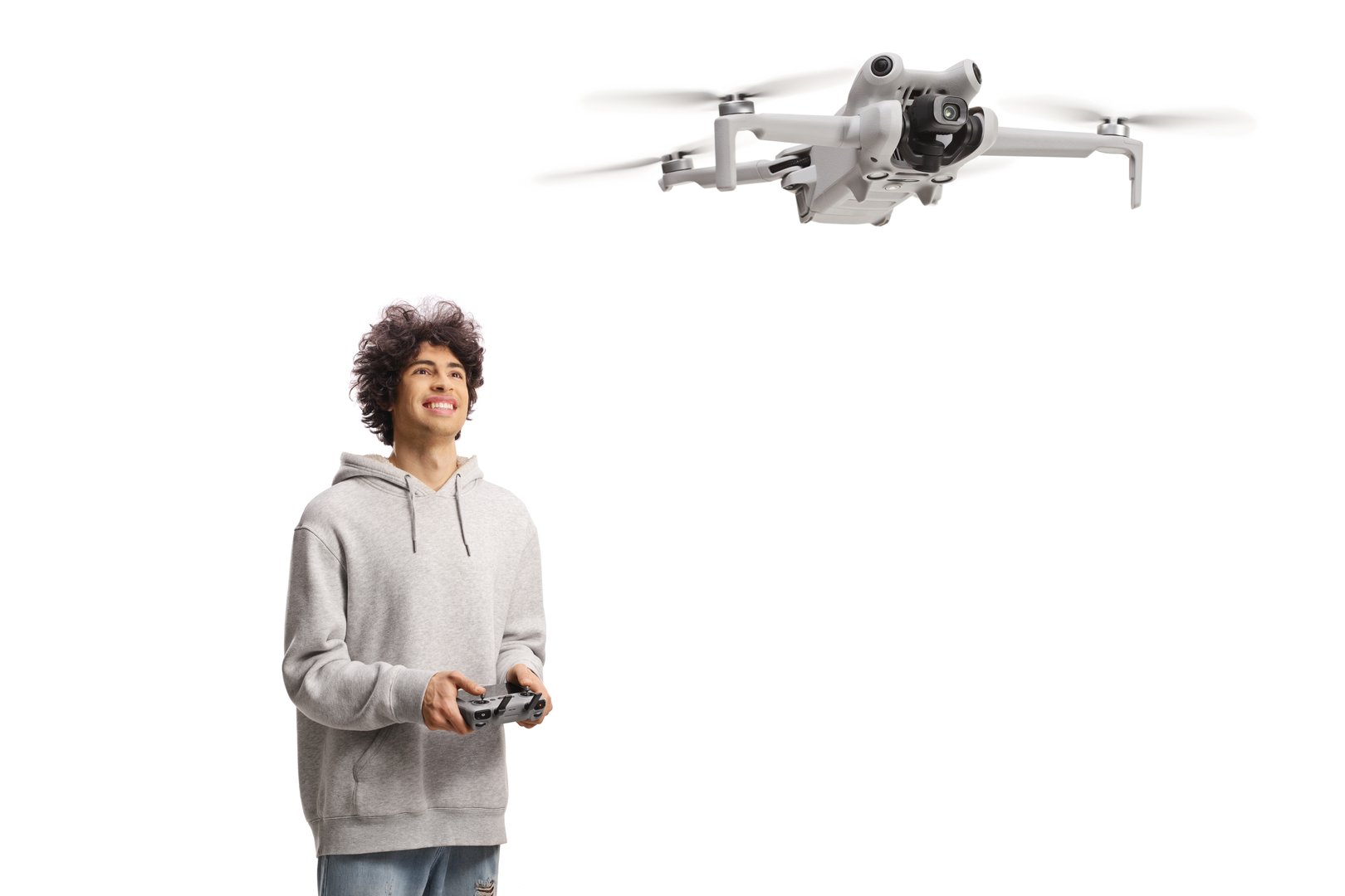 Happy young man flying a drone with a cotroller device and looking up isolated on white background