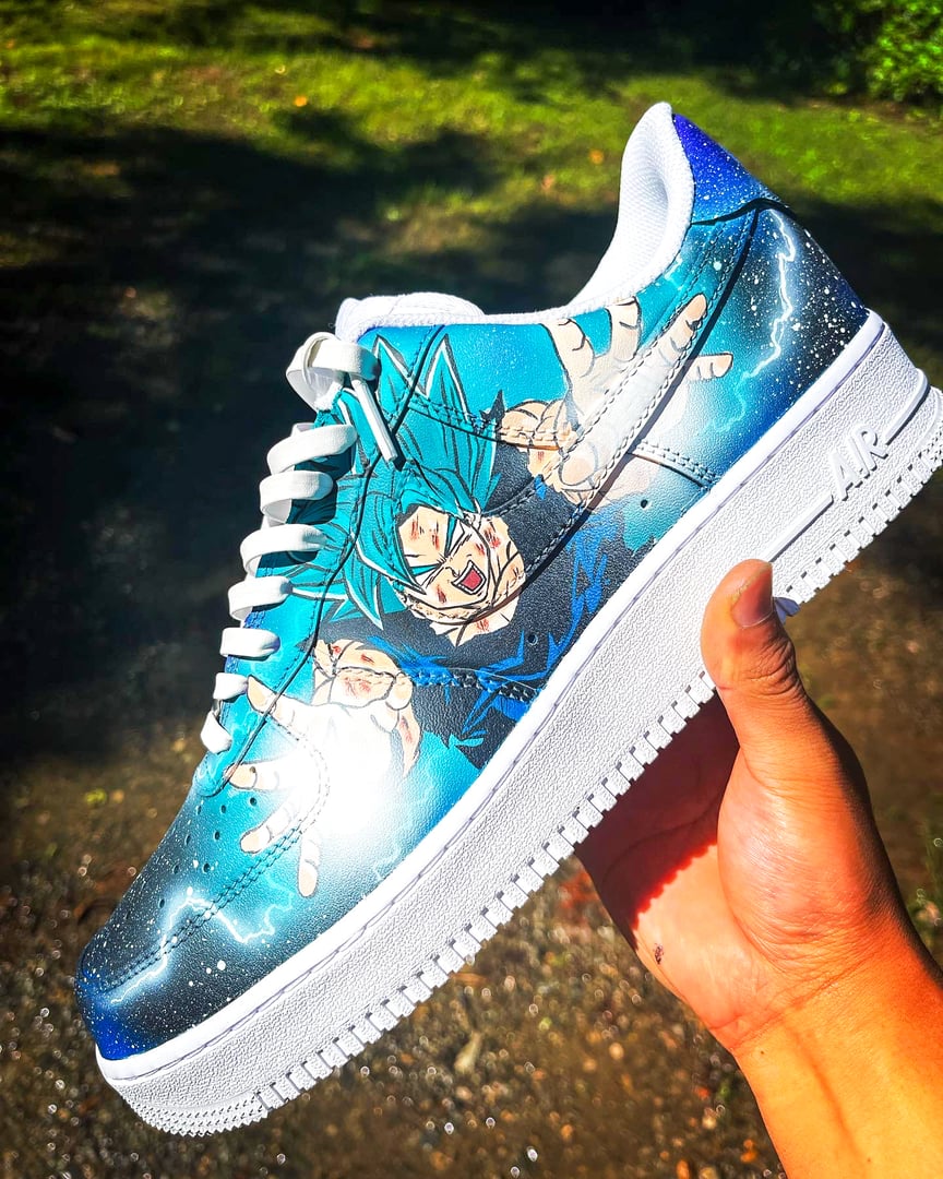 Custom Nike Air Force 1 sneaker with anime character design in blue and white, held up against a natural background.