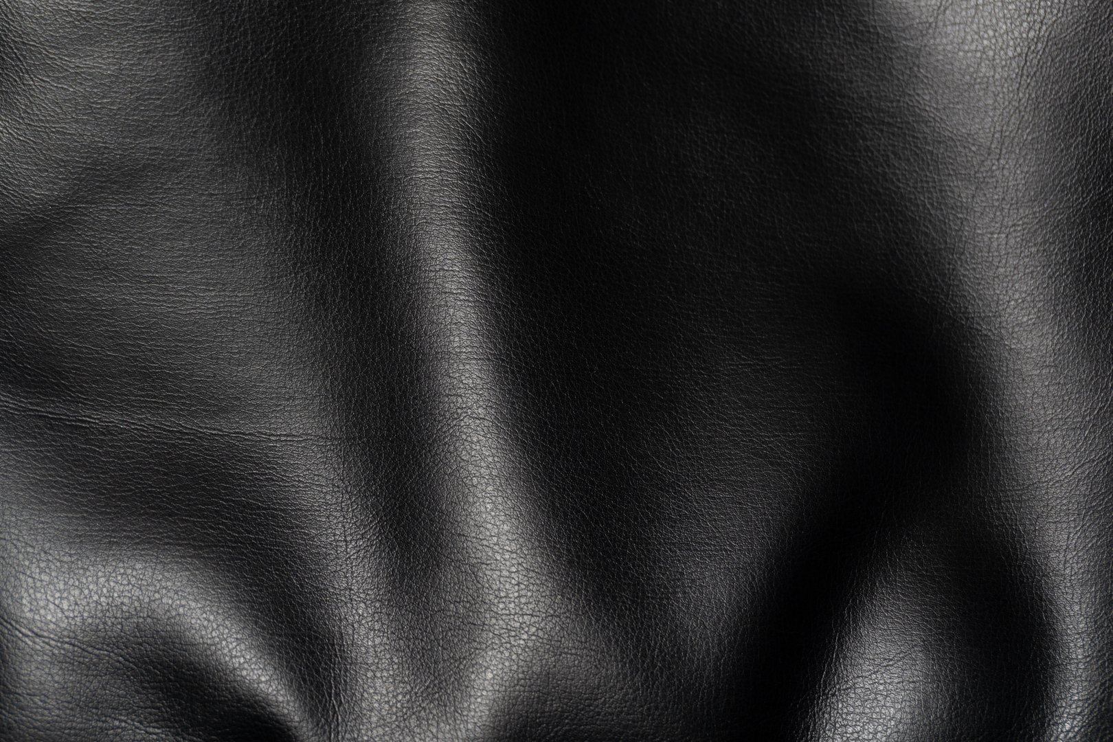 Curved black faux leather with pronounced folds and texture for high-end design. This photo emphasizes the material flexibility, creating a sense of dynamism.