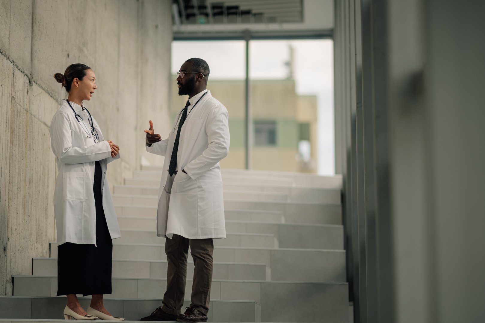 Two doctors are discussing a medical case on a hospital staircase, demonstrating collaboration and professional communication