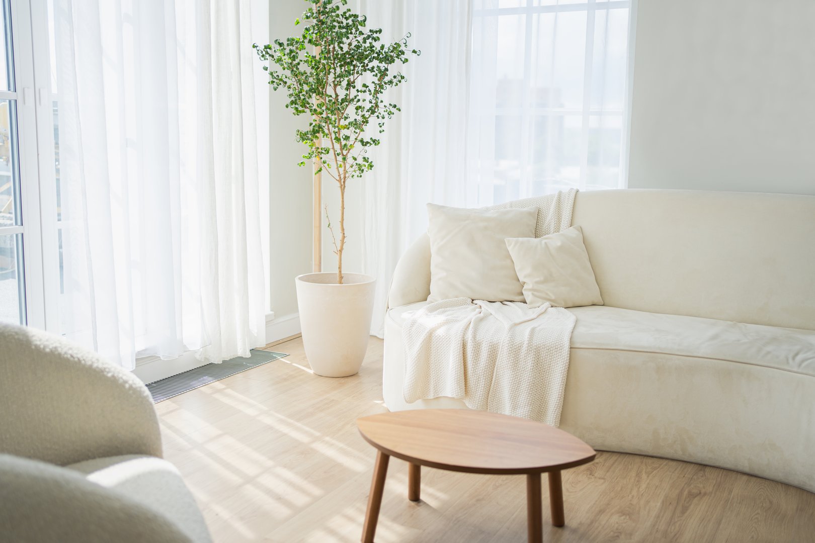 Stylish loft bedroom interior. Spacious design apartment with light walls large windows white couch sofa and armchair. Clean modern decoration with elegant furniture in minimalist Scandinavian style