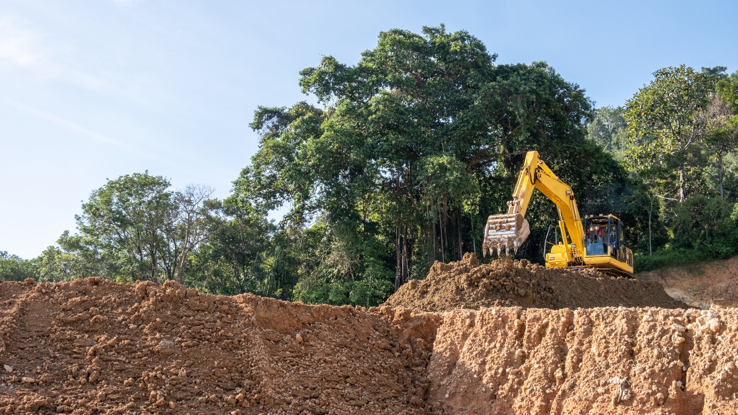 yellow excavator machine working in hills of tropical forest in indonesia