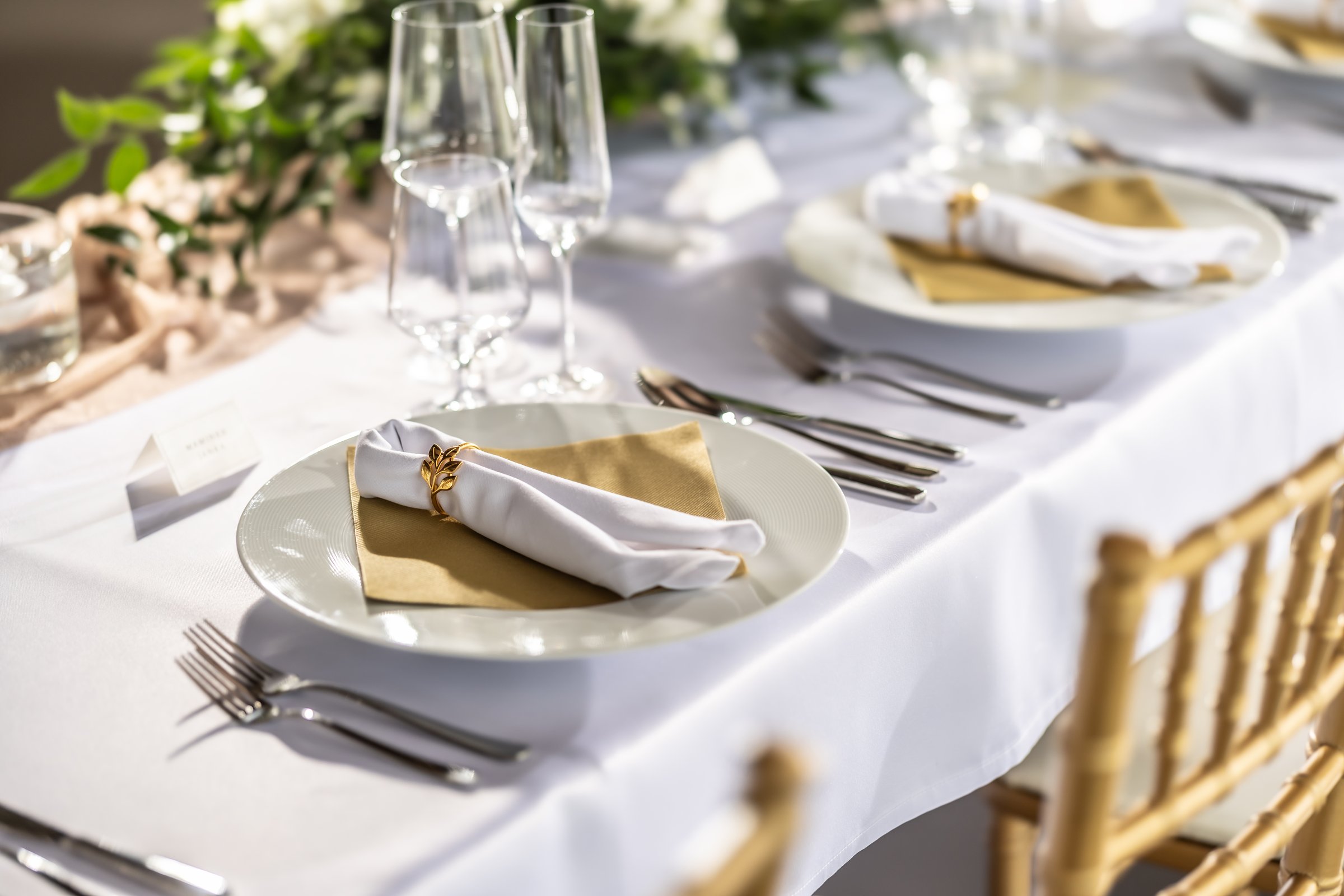 A wedding table covered with a white tablecloth, decorated with flowers, candles, glasses and cutlery.