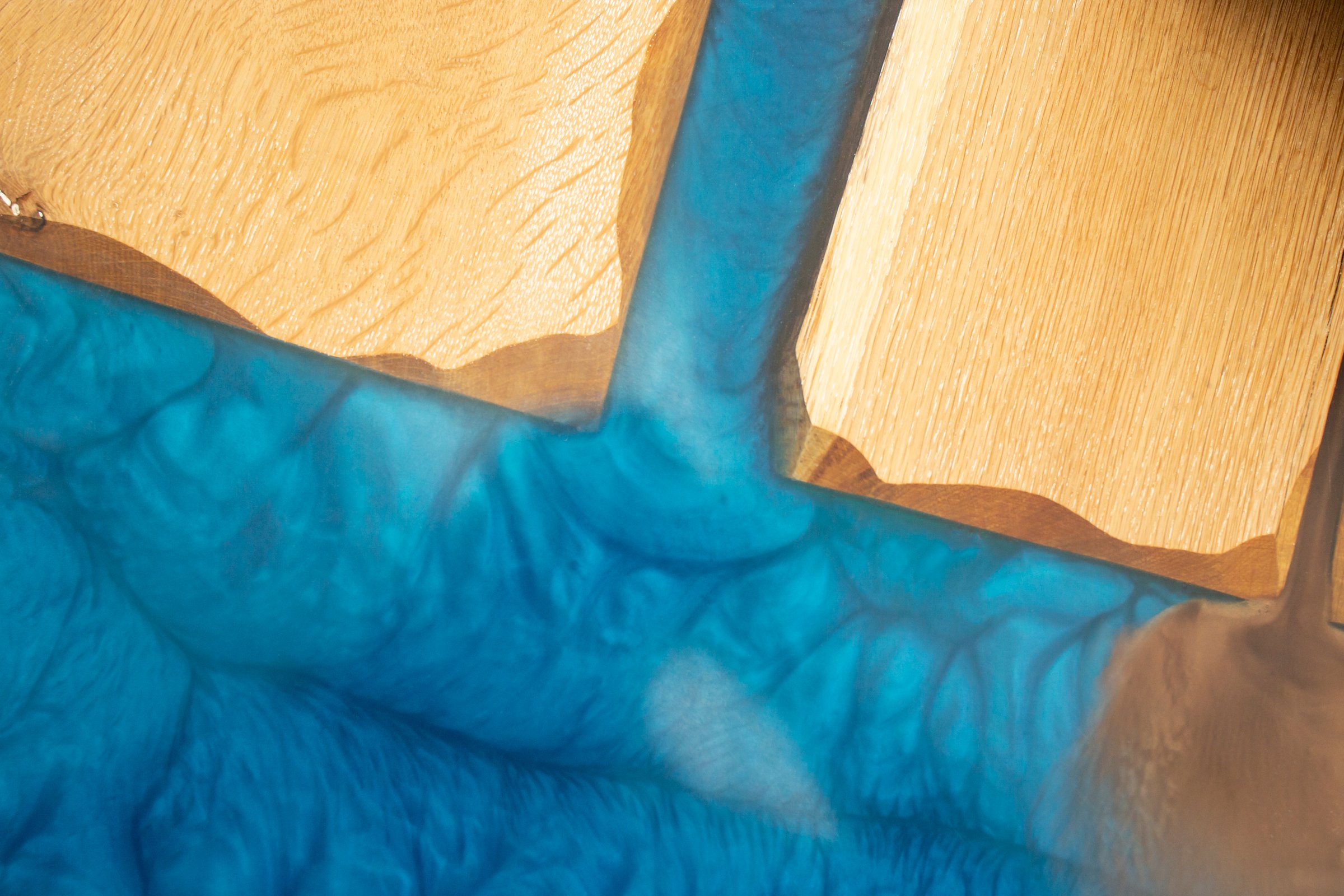 Blue epoxy resin and hard wood table detail, soft focus photography close up, abstract texture