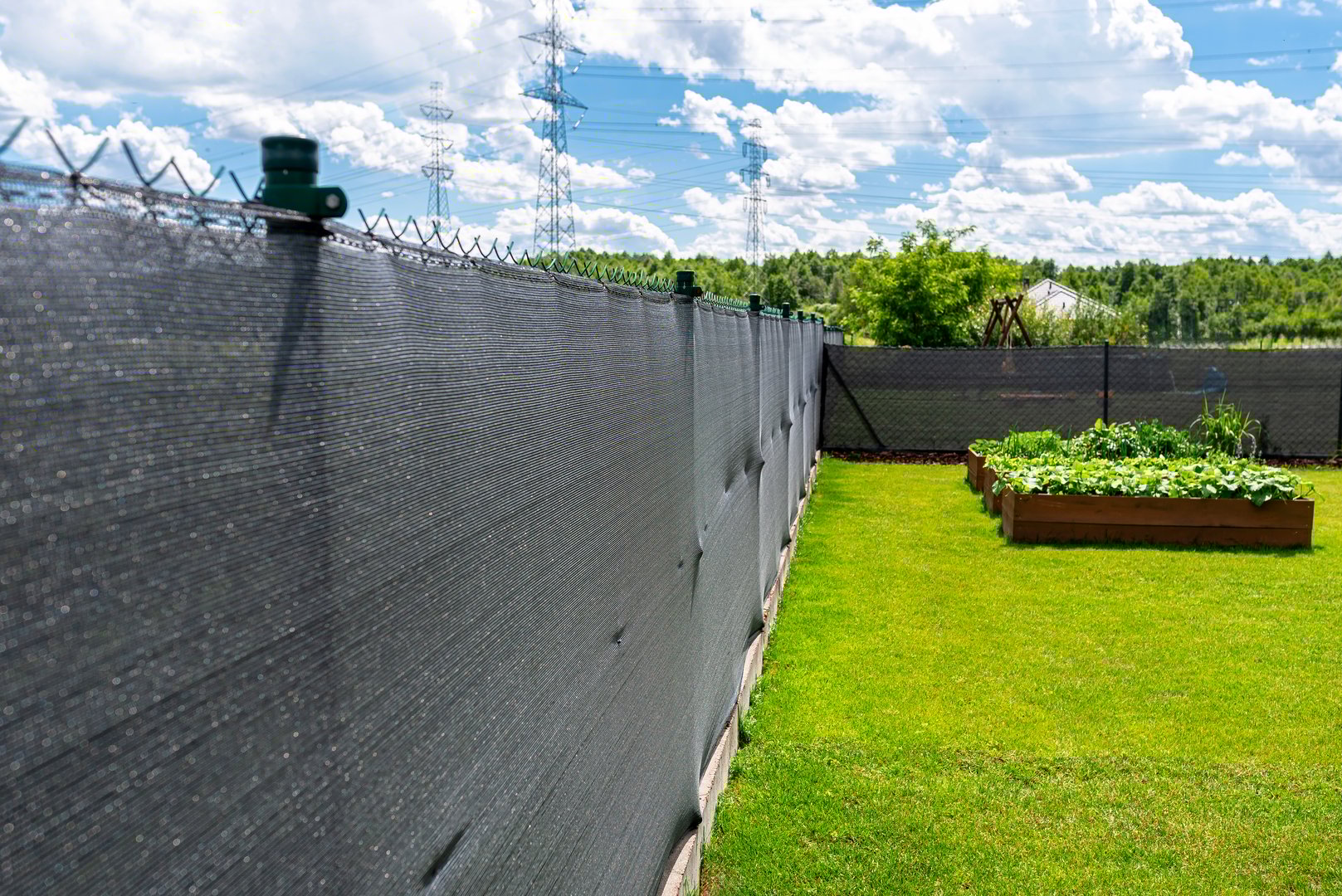 Anthracite-colored masking net placed on a mesh fence, visible vegetable boxes.