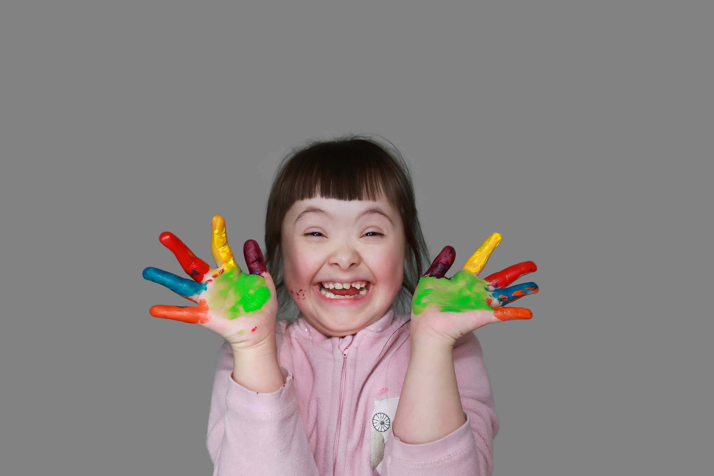 Cute little girl with painted hands. Isolated on grey background.