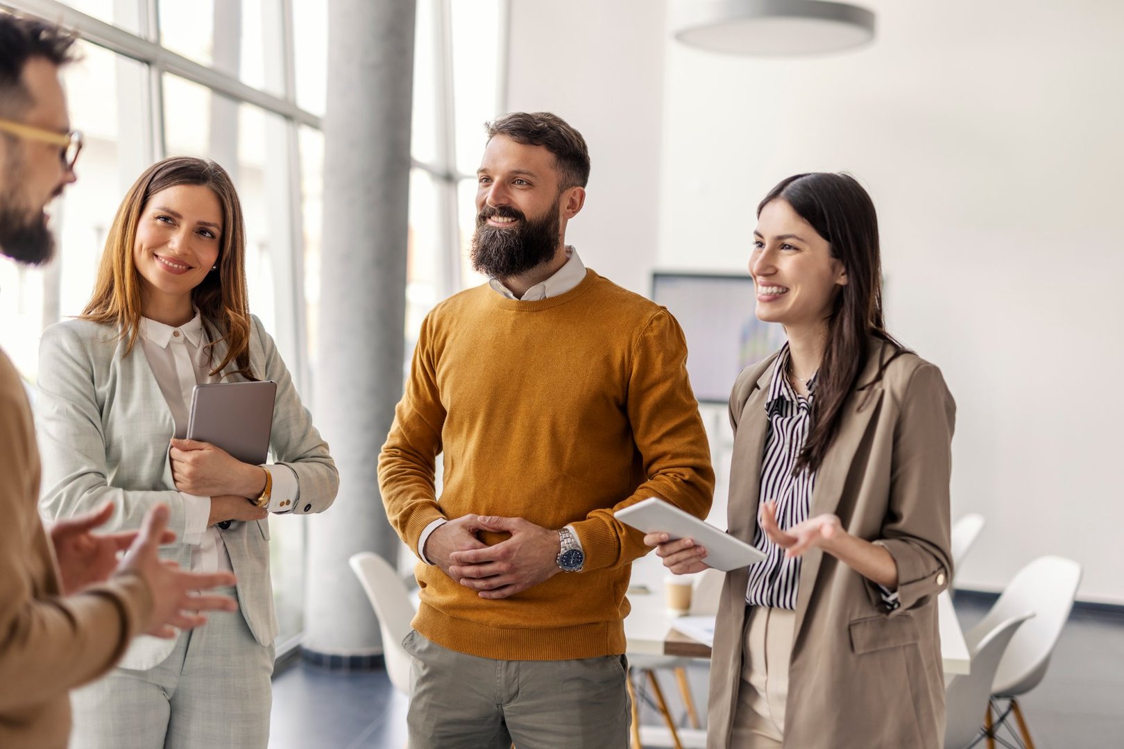 Smiling professional businesspeople standing at corporate office and collaborating on a new project.