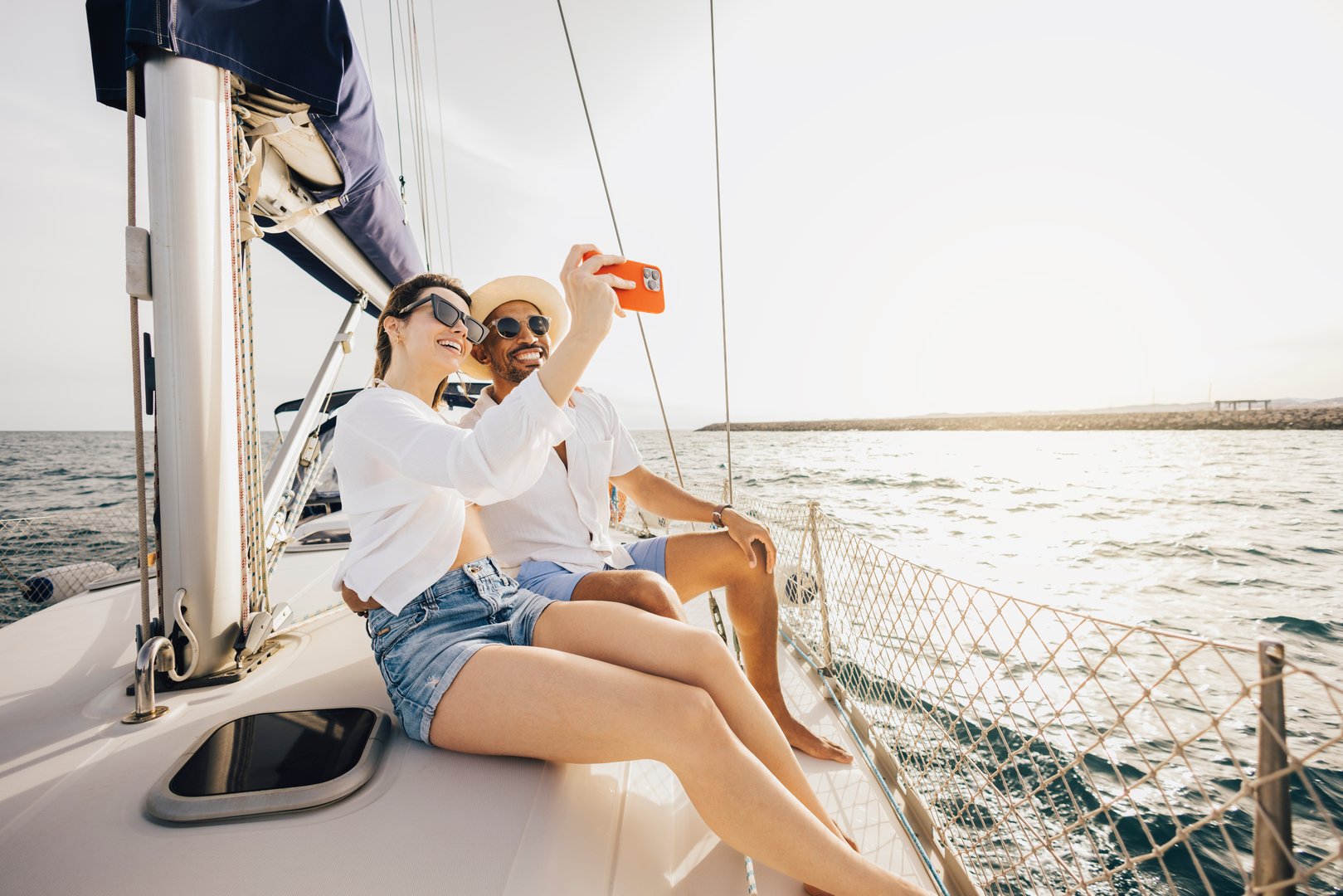 Happy couple enjoying a relaxing day on a sailboat, capturing memories with a selfie.