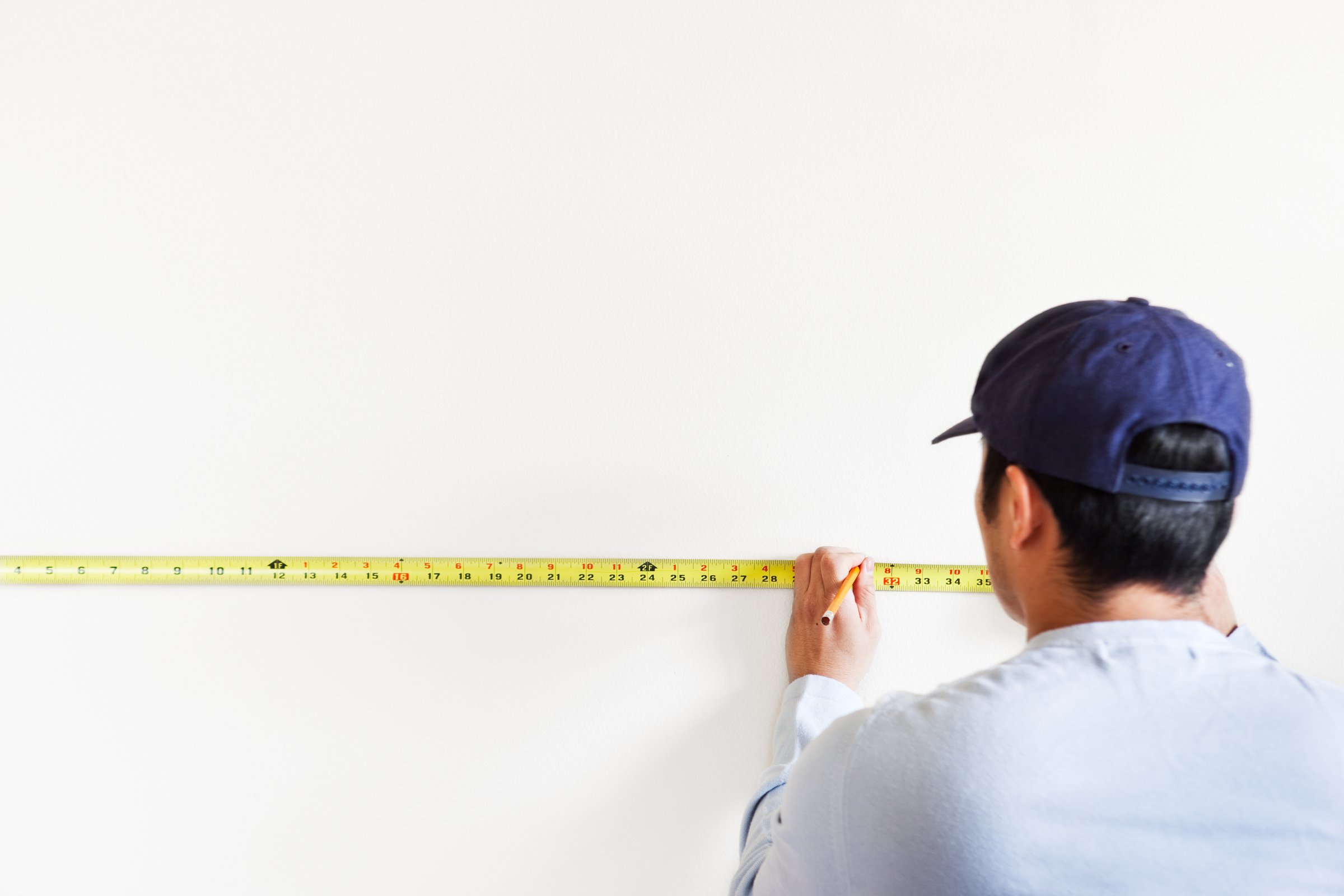 Professional remodeler measuring interior wall for renovation