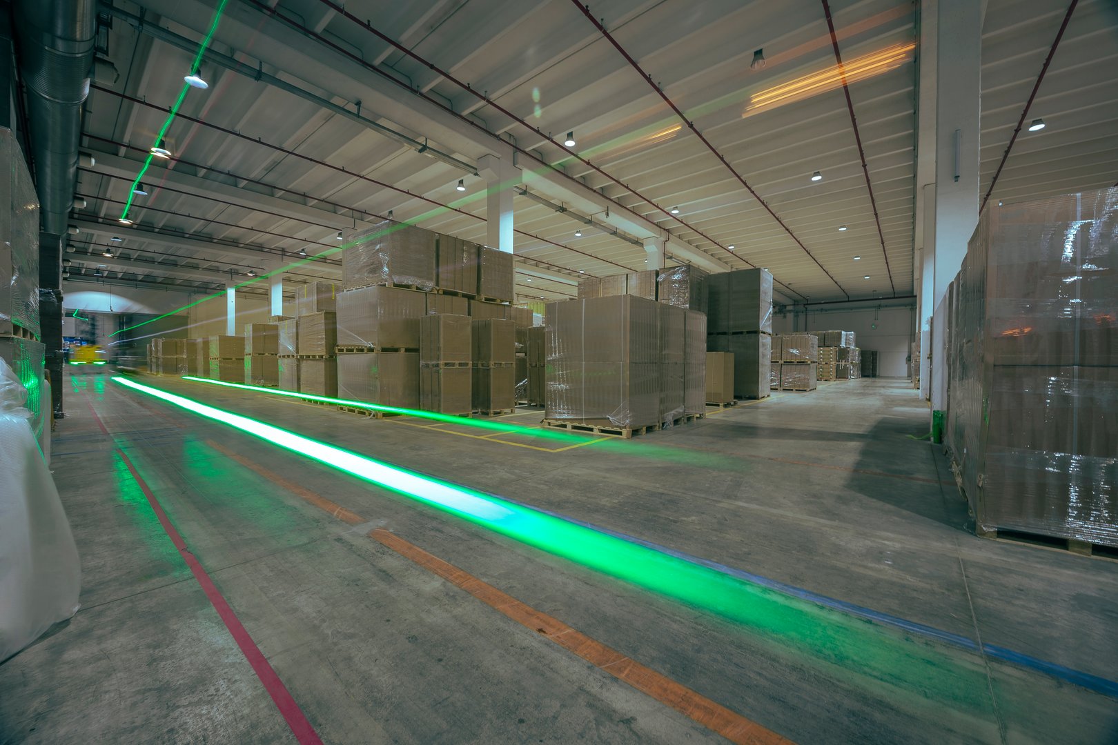 Light trails inside an automated warehouse where shipments are digitally controlled by artificial intelligence. No people are visible.