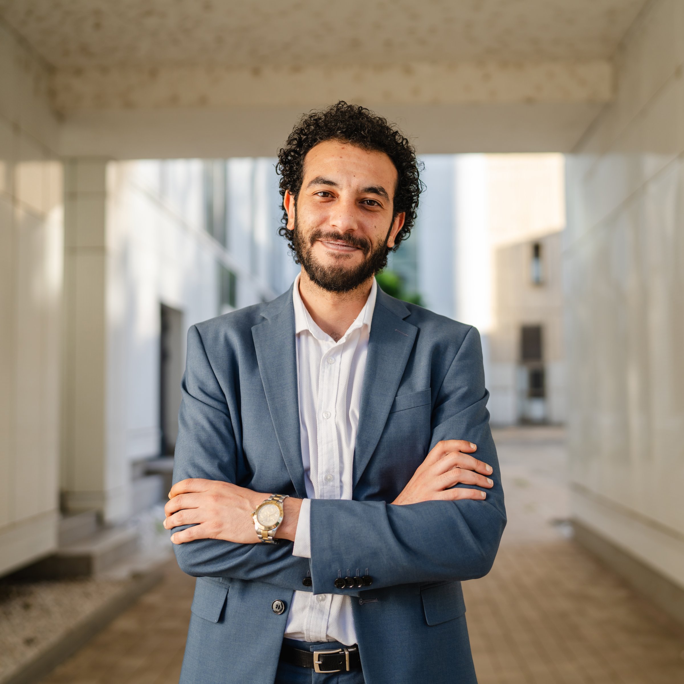 Confident businessman is smiling with crossed arms, exuding professionalism and success in a modern office building, showcasing leadership and achievement in corporate environment