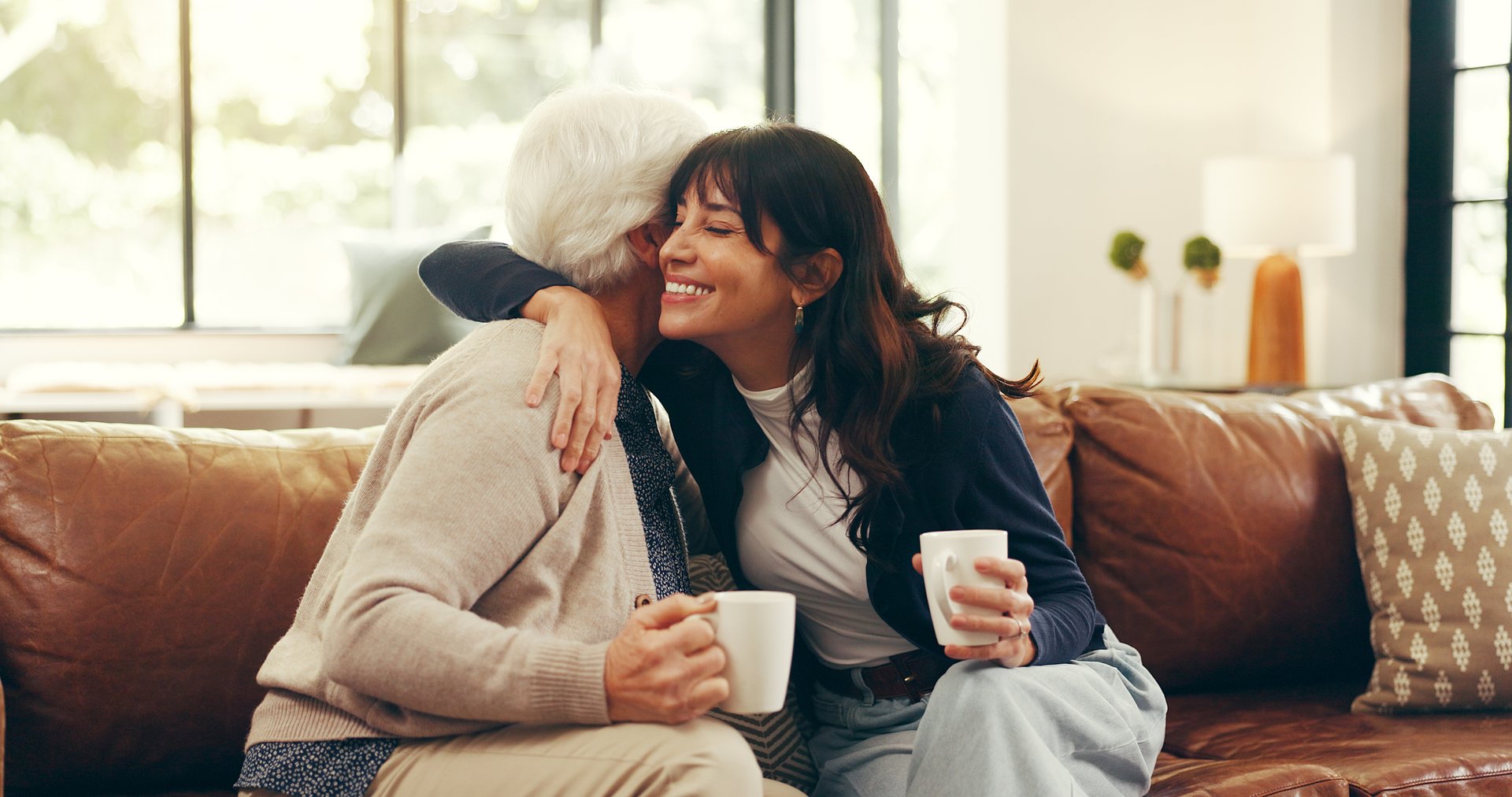 Relax, coffee and hug with senior mother and daughter on sofa for love, bonding or support