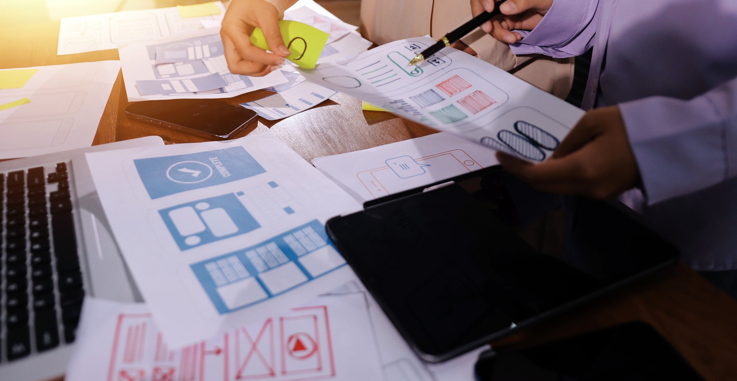 Close up ux developer and ui designer brainstorming about mobile app interface wireframe design on table with customer breif and color code at modern office.Creative digital development agency.