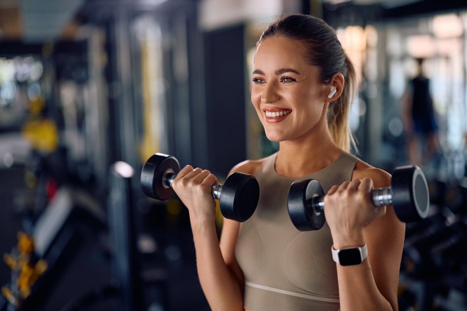 Happy athletic woman using dumbbells during gym workout