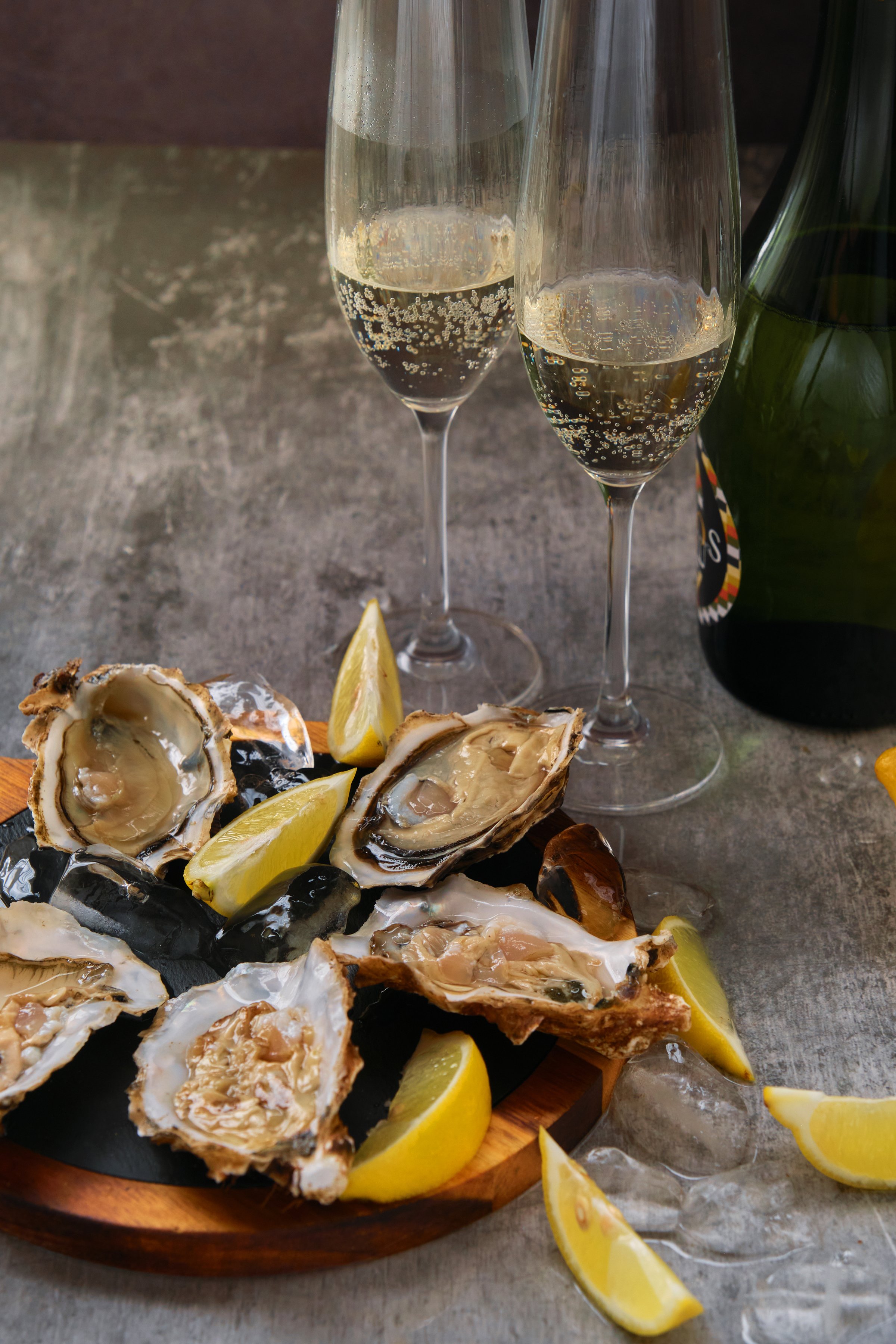 open oysters on a board with lemon slices and a glass of champagne