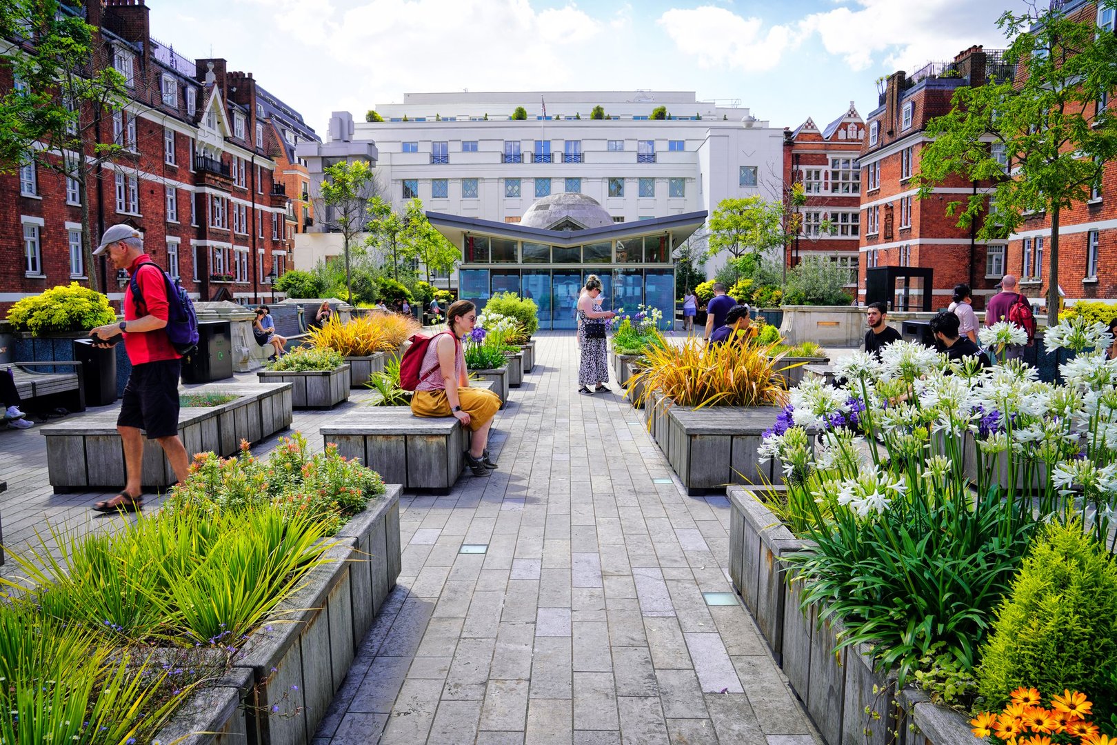 Mayfair, London, England, the United Kingdom, July 18, 2024 – Brown Hart Gardens on a summer day, building features, street photography.a typical scene in one of London's central parks. popular spot for Londoners and tourists alike, during lunch break, sunny day. Park benches in London park, Flowers and plants, landscaping, People enjoying lunch, tourists Sunbathing, summer nature and urban life, people to enjoy outdoor activities, relax in the heart of the city.