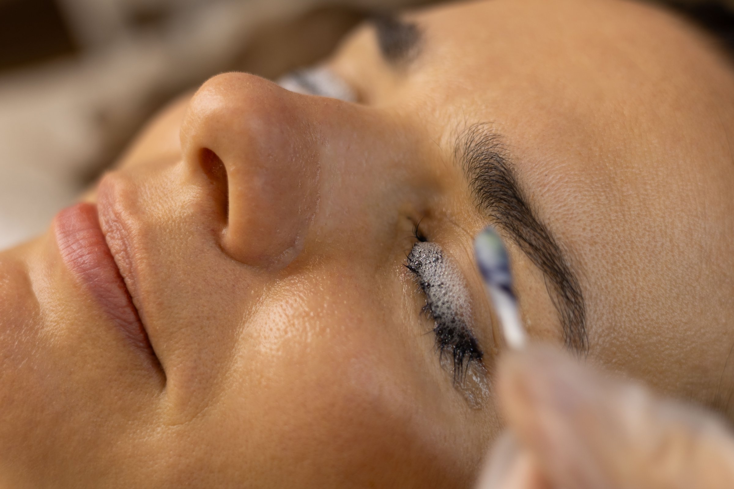 The make-up artist does eyelash lamination. She paints eyelashes, shapes eyebrows, curls eyelashes, applies dye and certain
