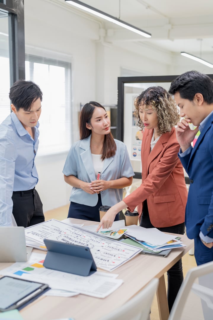 Creative Asian professionals brainstorming in a modern office. Business team collaborating on innovative ideas and strategies in a contemporary workspace, emphasizing teamwork and dynamic thinking