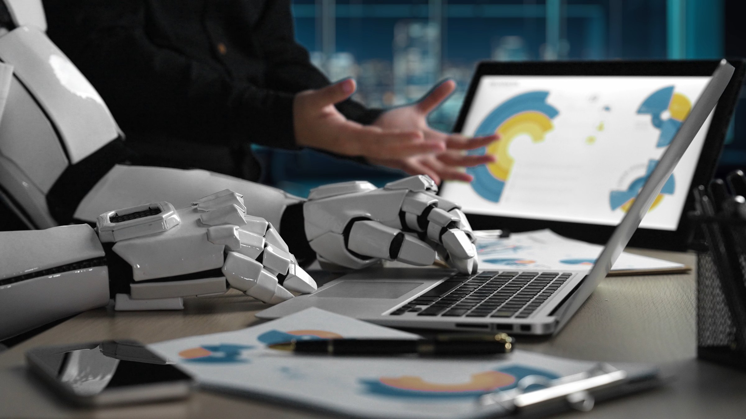 A sleek robotic arm interacts with a laptop and documents in a modern workspace, showcasing the blend of technology and innovation in today's digital environment.Noogenesis