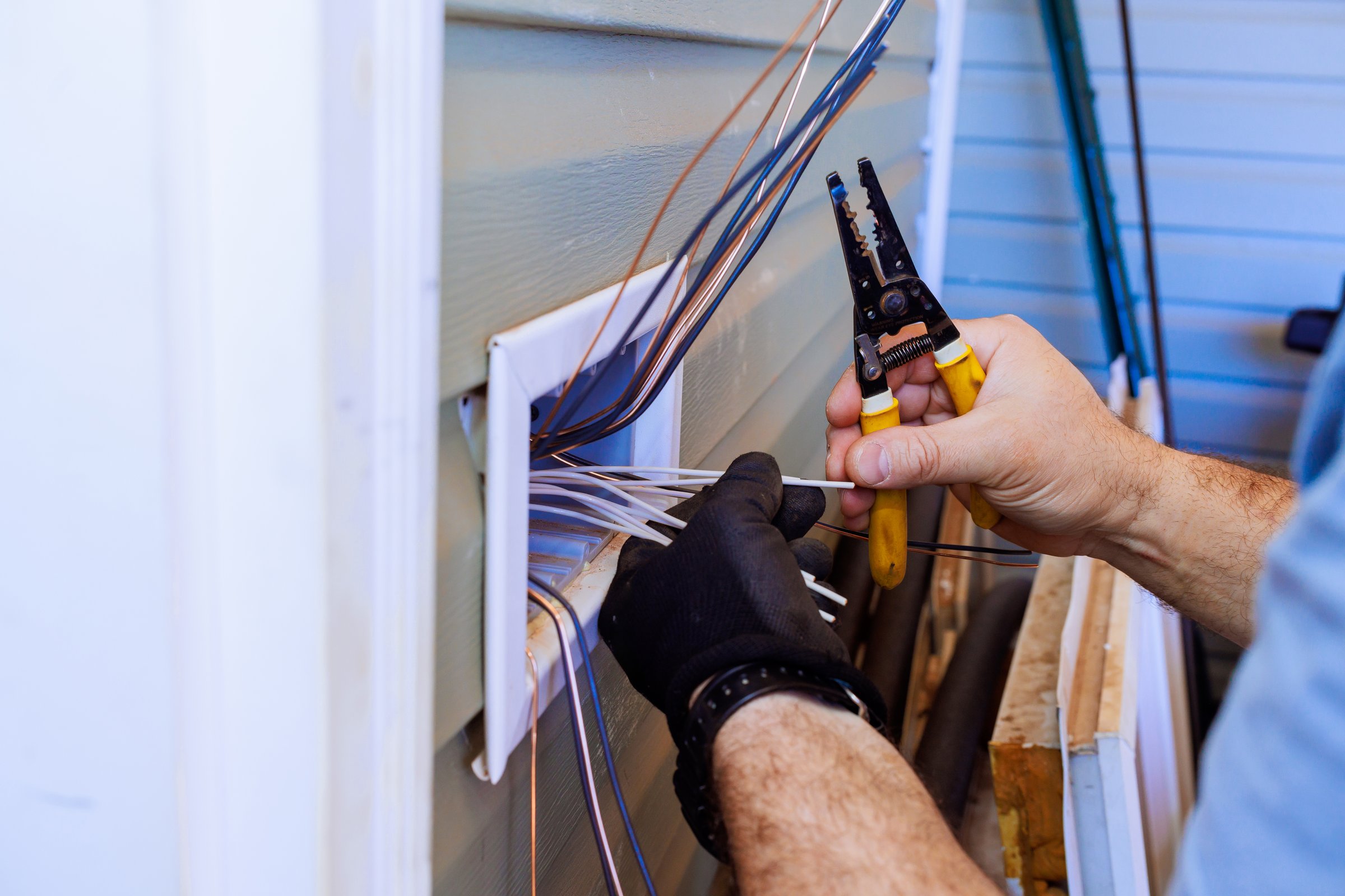 Contractor electrician uses tools to connect wires while during electrical work.
