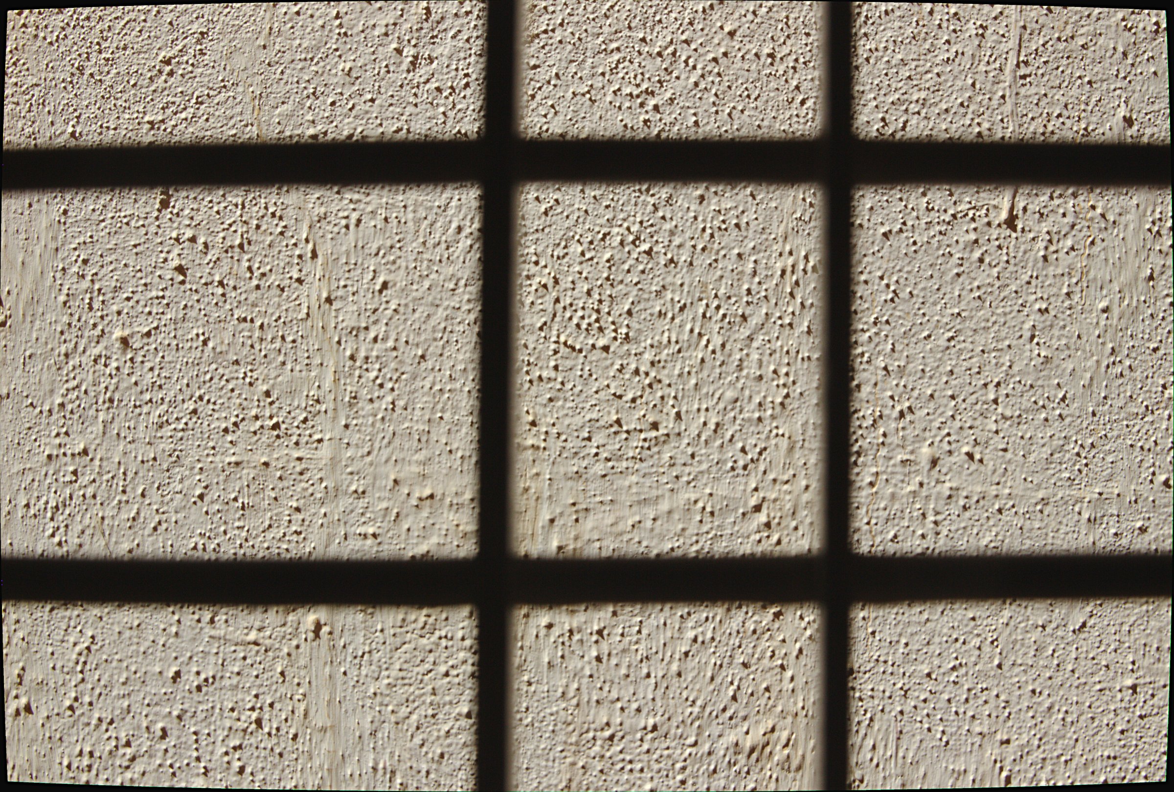 Gray colored, textured, concrete wall viewed through window frame