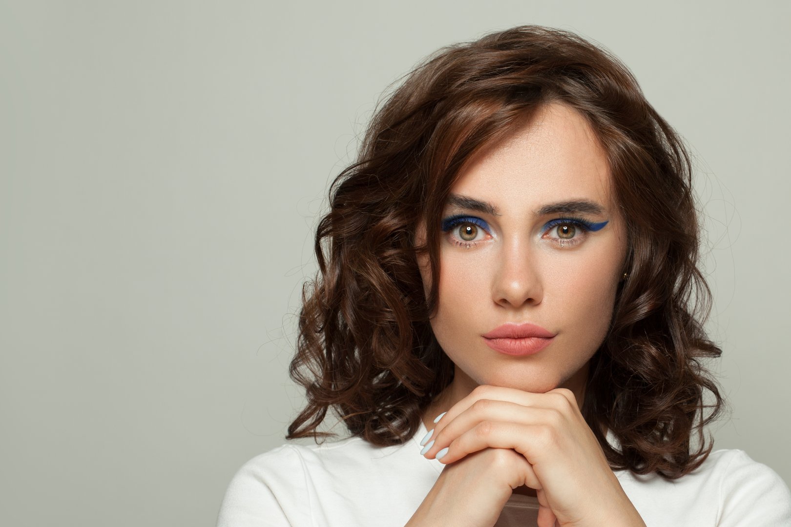 Young pretty woman with perfect curly hair and healthy clear skin on white background