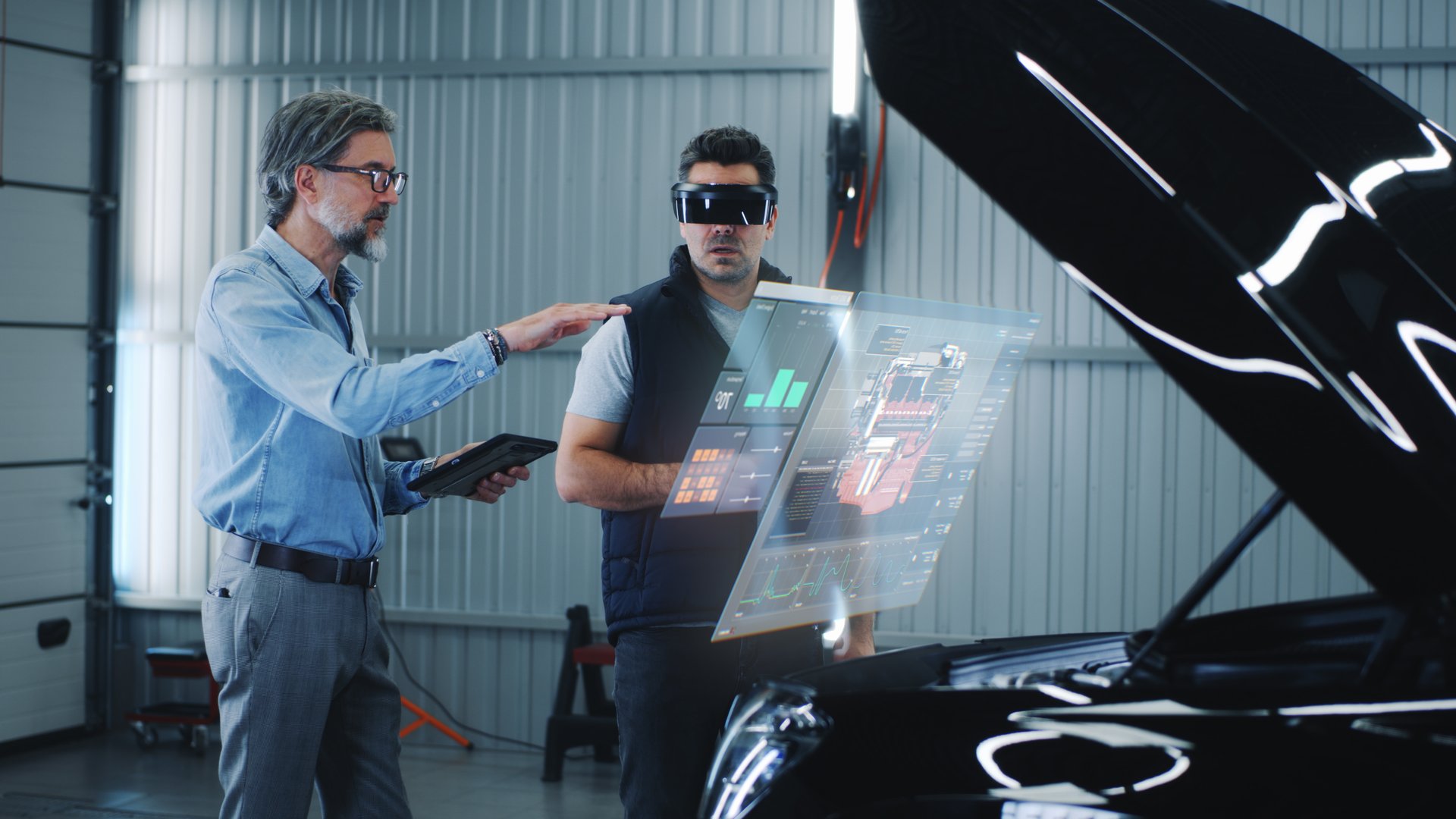 Two specialists carry out car diagnostics using modern tools. They study the indicators and graphs on the screen, displaying the condition of the car. Carrying out repairs in a technological workshop.