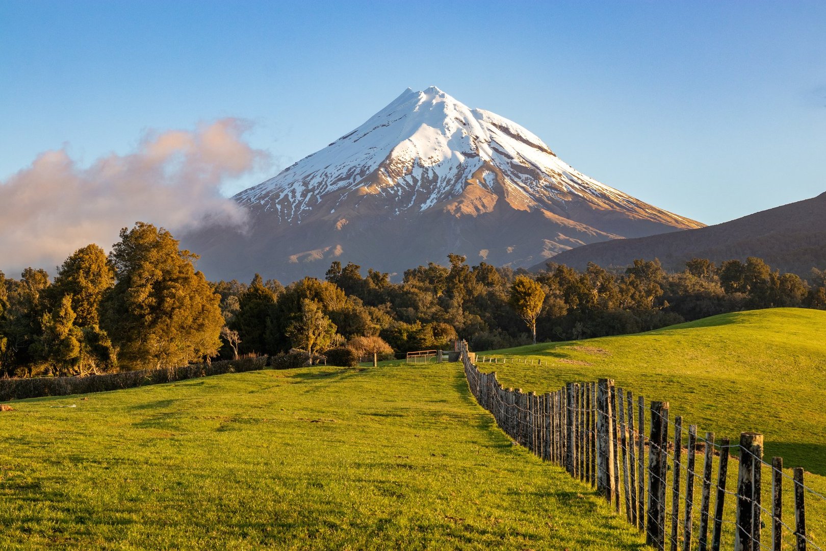 Taranaki volcano and picturesque farmland landscape at sunset, New Zealand