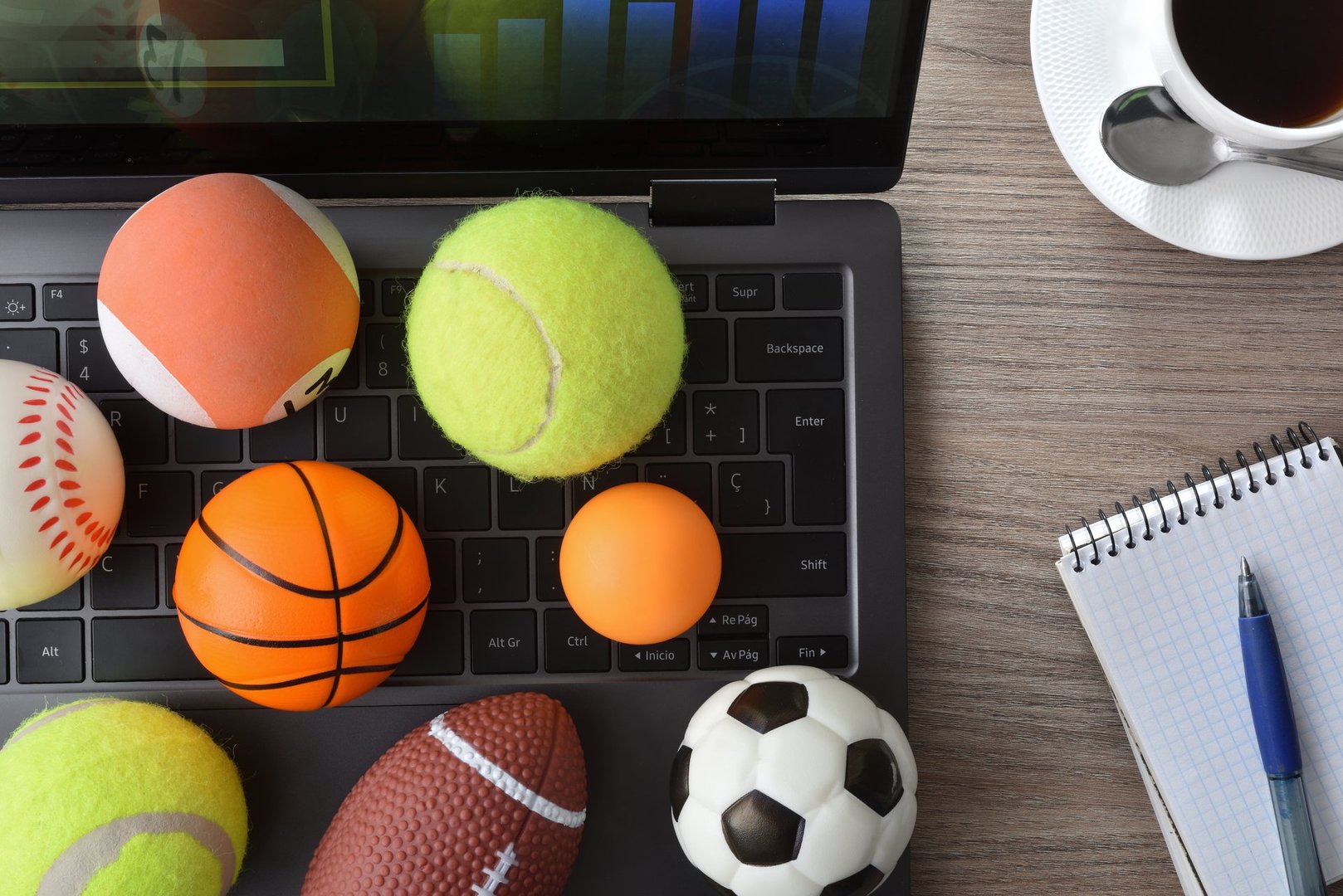 Concept of entertainment with technology in sports with laptop with an analysis application and game results on an office table with balls. Top view.
